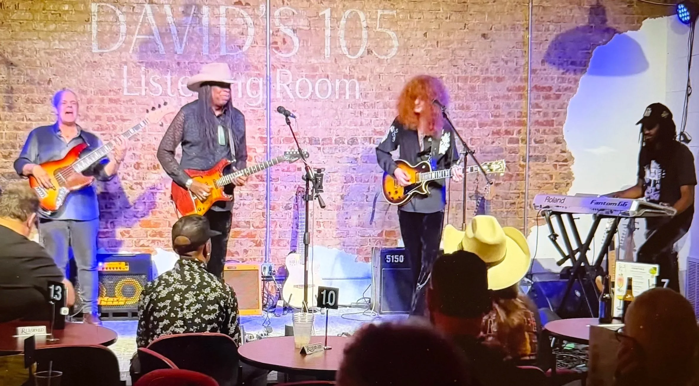 Live music performance at a venue called David's 105 Listening Room with two musicians playing guitars and an audience sitting at tables.