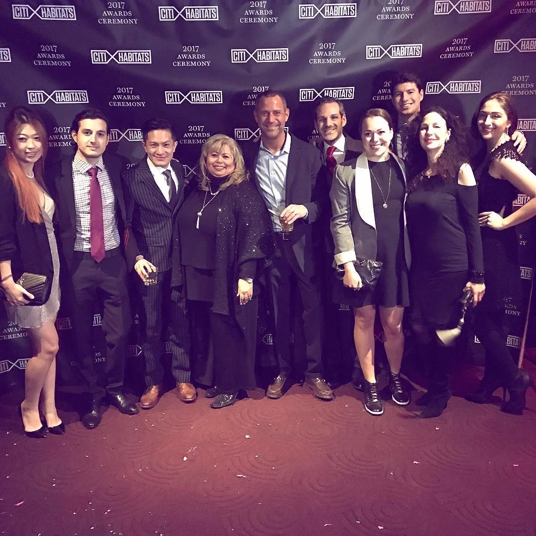 A group of ten people dressed in formal attire posing for a photo at an awards ceremony backdrop. The backdrop displays '2017 Awards Ceremony' and 'Citi Habitats' logos.