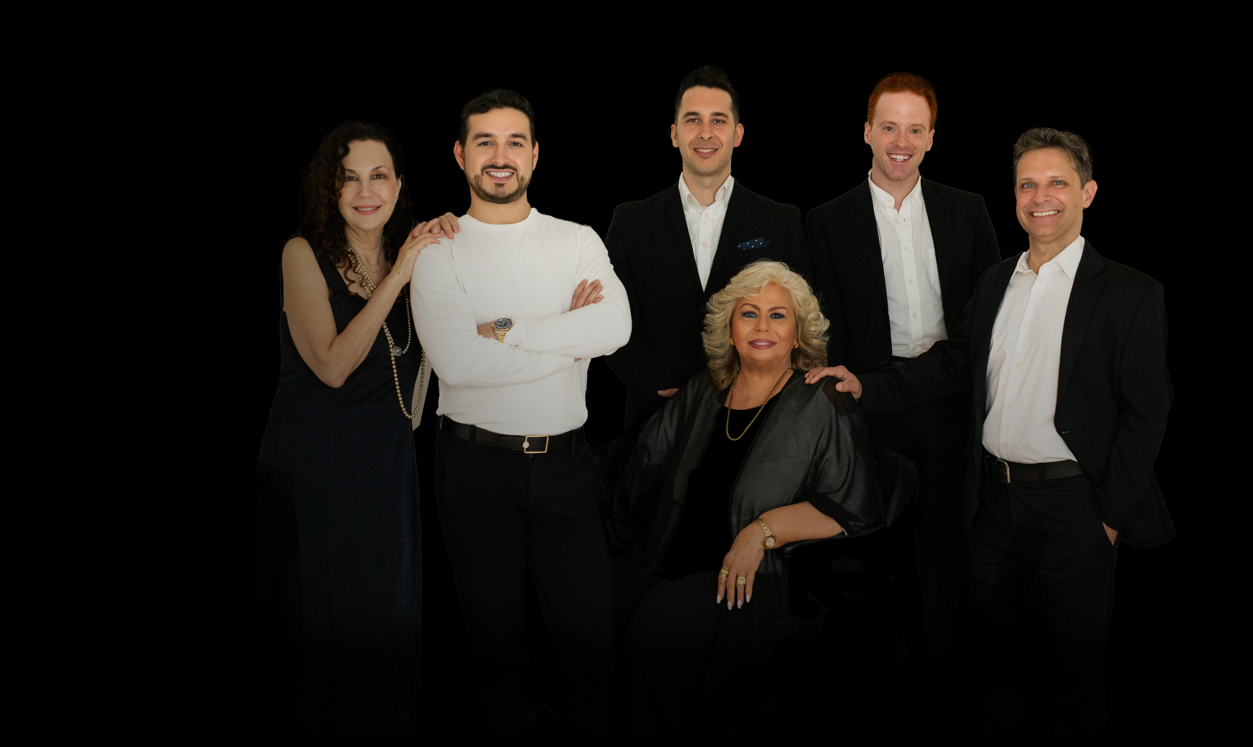 Group of seven professionally dressed people, four men and three women, posing against a black background.