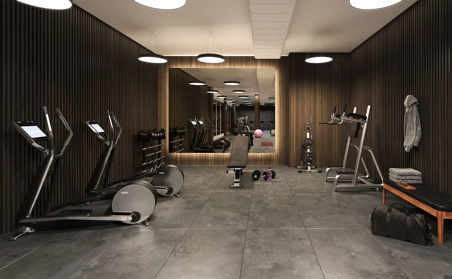 Modern gym with cardio machines, weights, and workout equipment on a polished gray floor, with dark wood panel walls and ceiling lights.