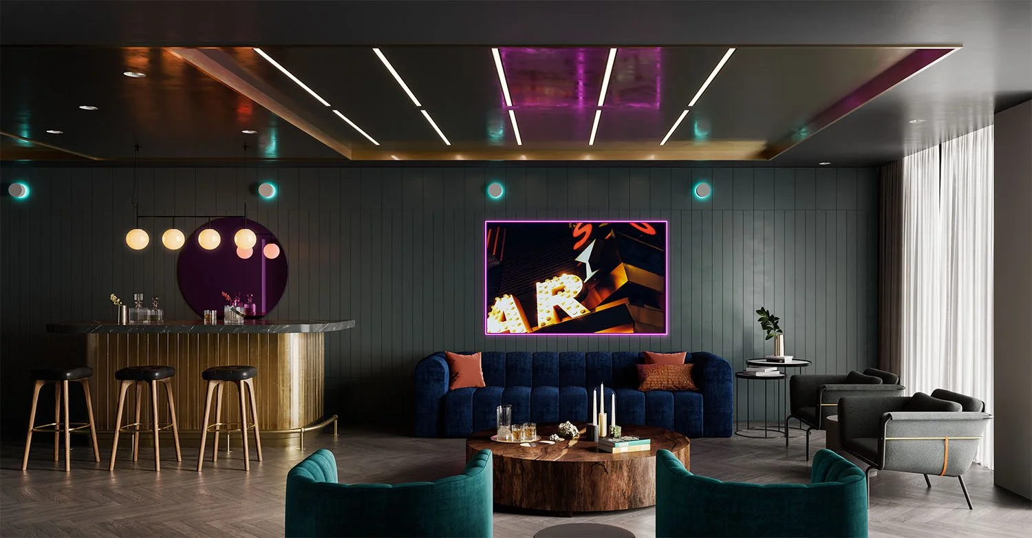 Modern lounge with navy sofa, green armchairs, round wooden coffee table, and a bar with stools, illuminated by colorful neon and pendant lights.