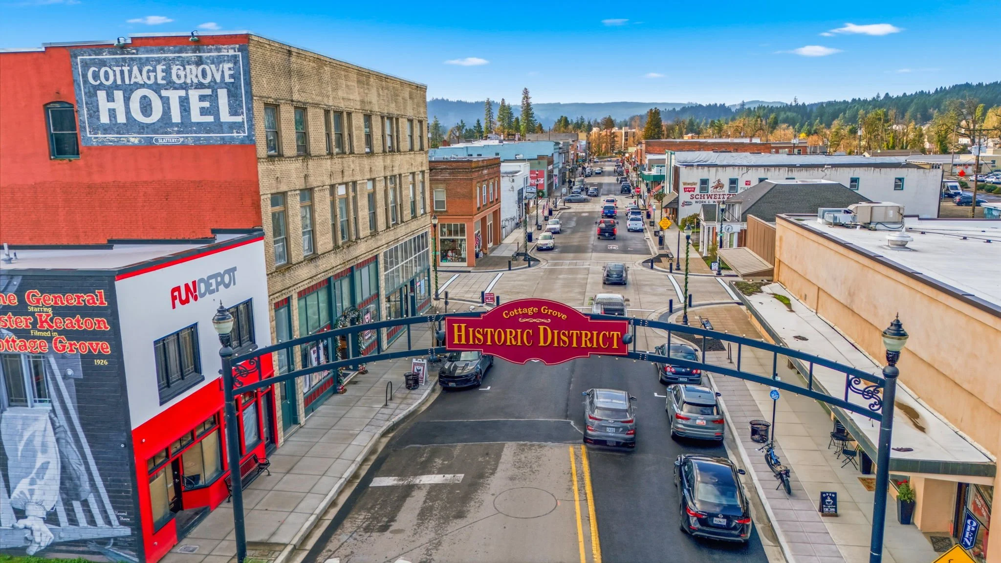 View of downtown Cottage Grove, Oregon, with a sign for the historic district, parked cars, shops, and buildings in a small town