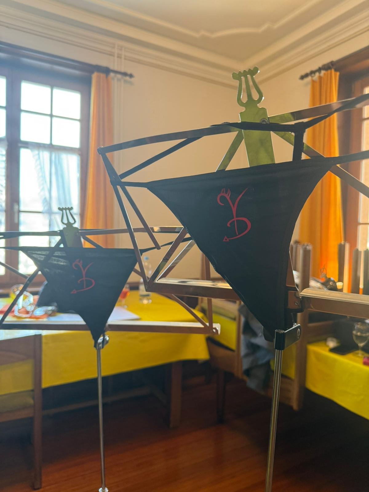 Modell eines Segelboots mit schwarzen Segeln und gelber Mastspitze, in einem Raum mit gelben Tischdecken und großen Fenstern