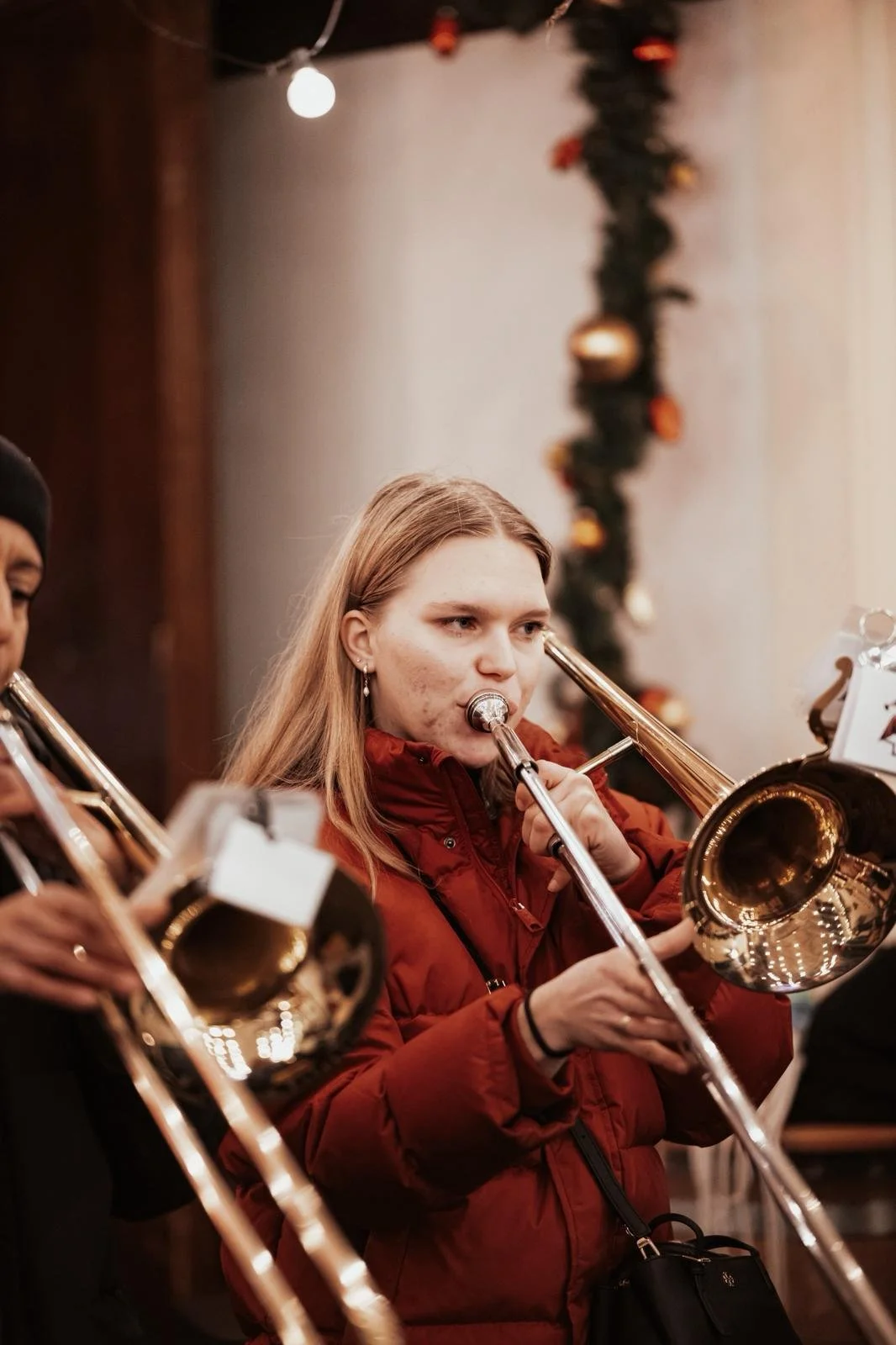 Junge Frau spielt Tuba bei einem Weihnachtskonzert, im Hintergrund Weihnachtsdekoration.