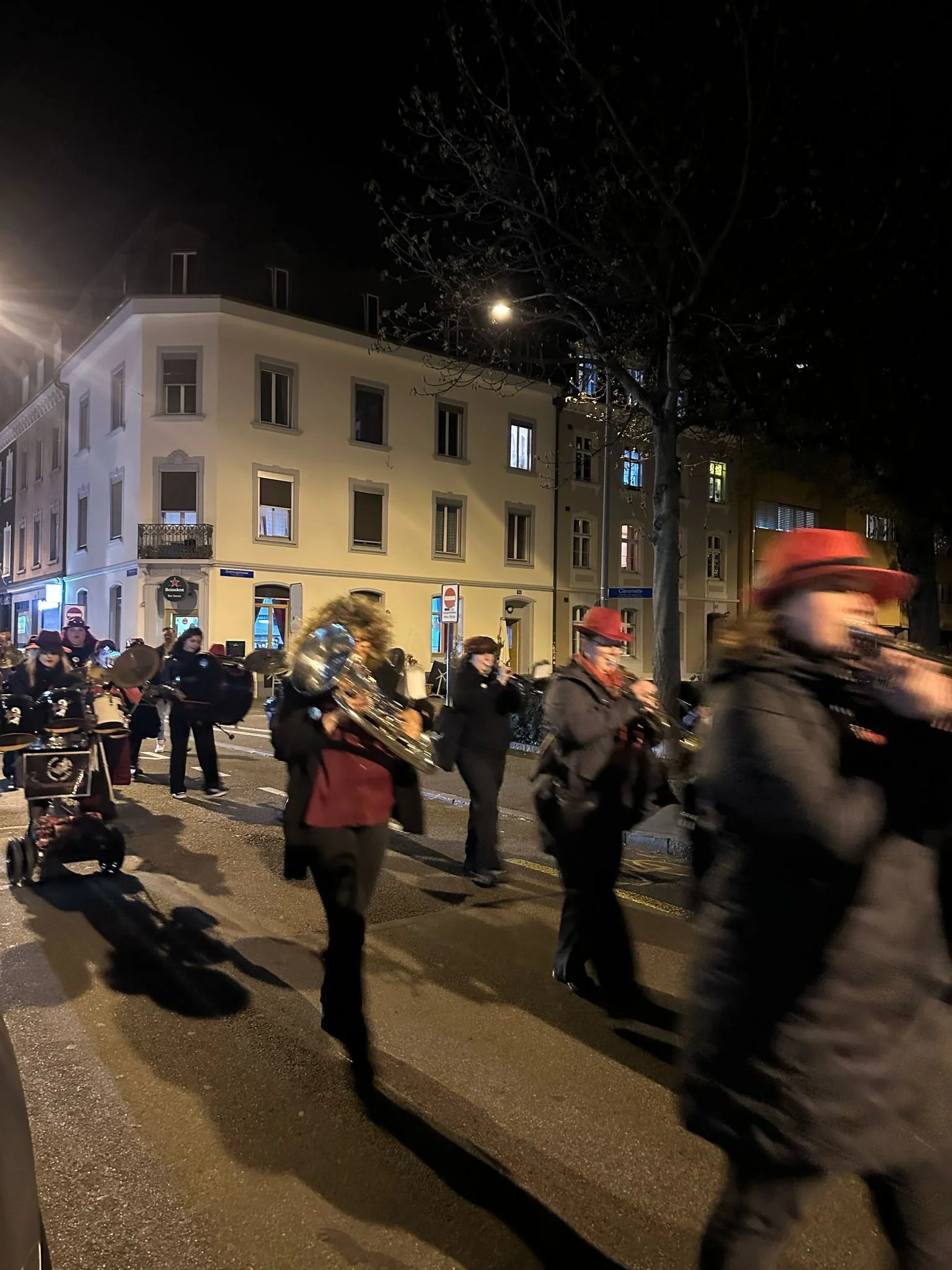 Musiker, die nachts auf einer Straße in einer Stadt marschieren, spielen Instrumente, einige tragen Hüte.
