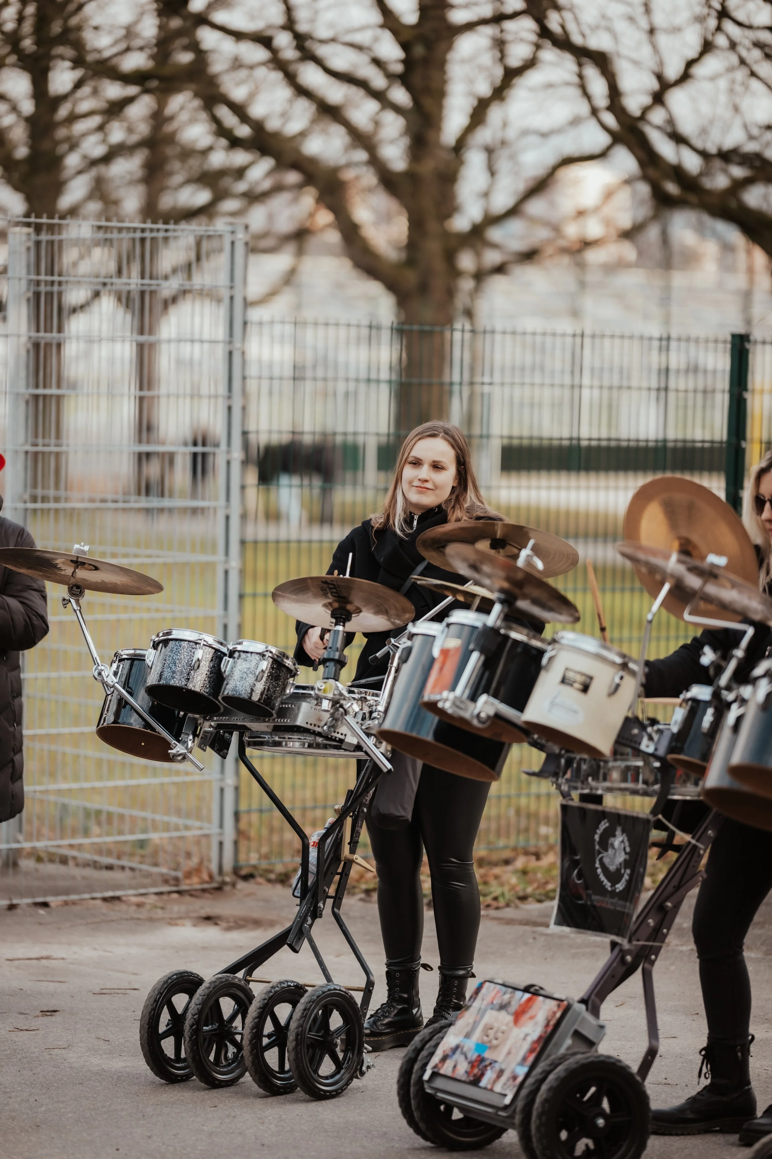 Junge Frau spielt Percussion-Instrumente auf einer Straße im Freien.