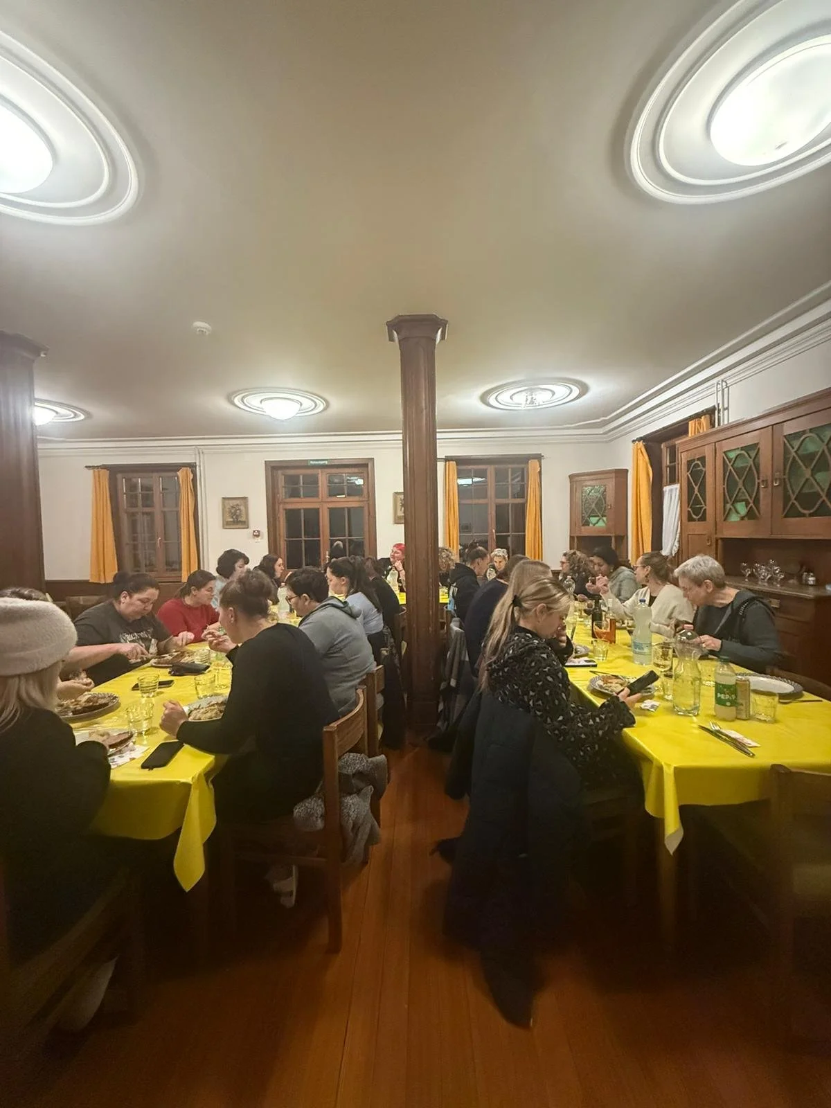 Menschen sitzen an einem langen Esstisch in einem gut beleuchteten Restaurant und essen.