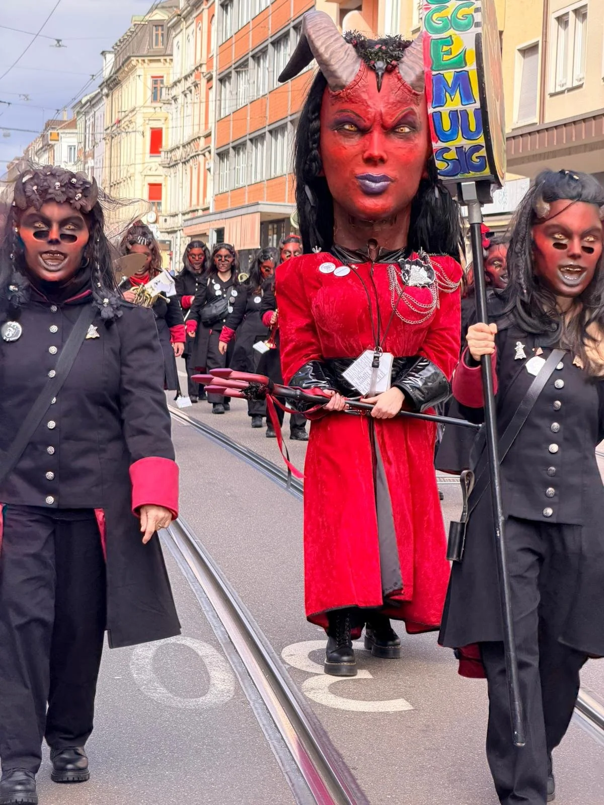 Menschen in Karnevalskostümen, hauptsächlich mit Dämonen- oder Teufel-Motiven, die an einem Straßenumzug teilnehmen.