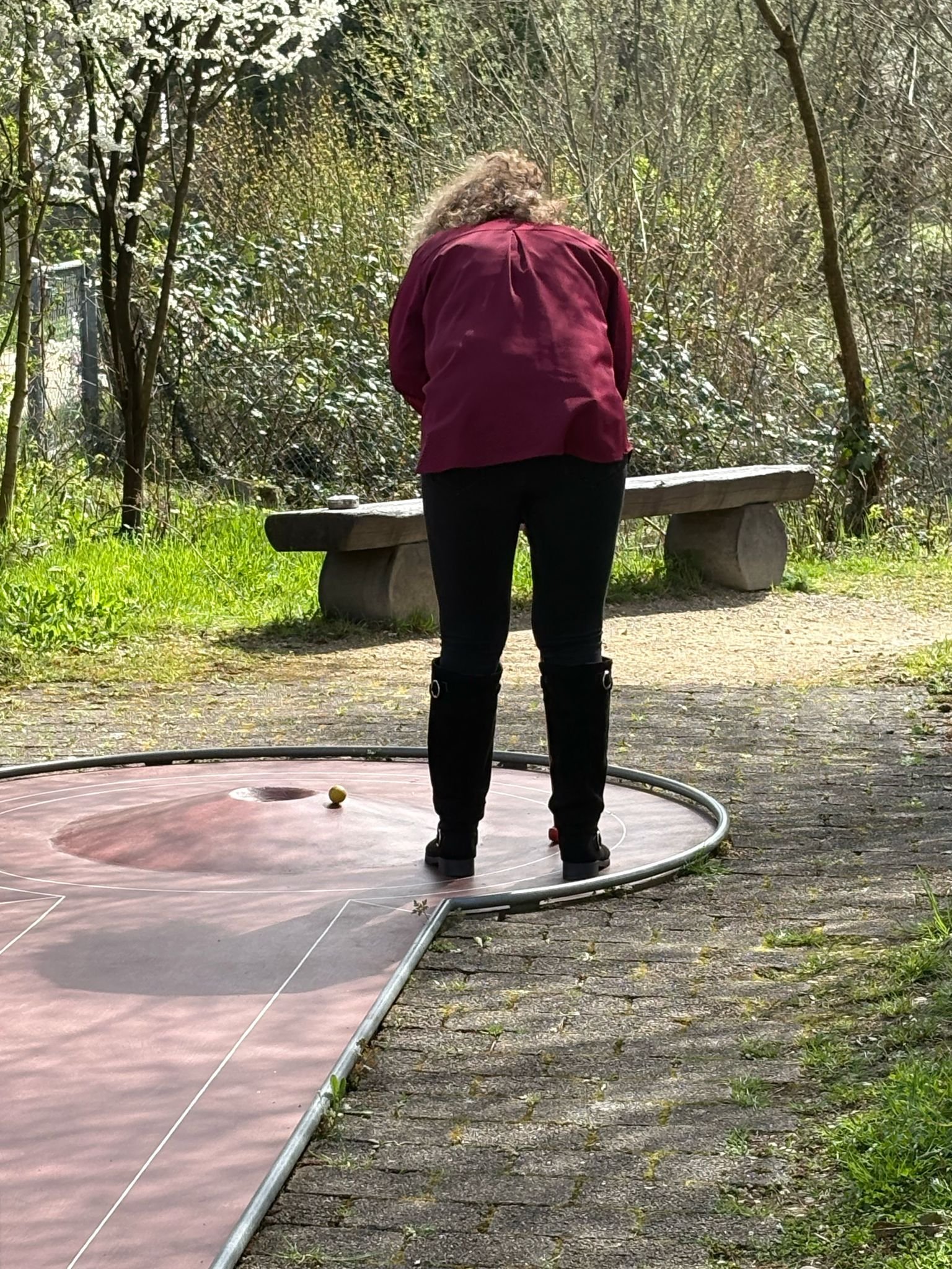 Frau beim Minigolf auf einem Platz im Freien, die auf einen Ball richtet.