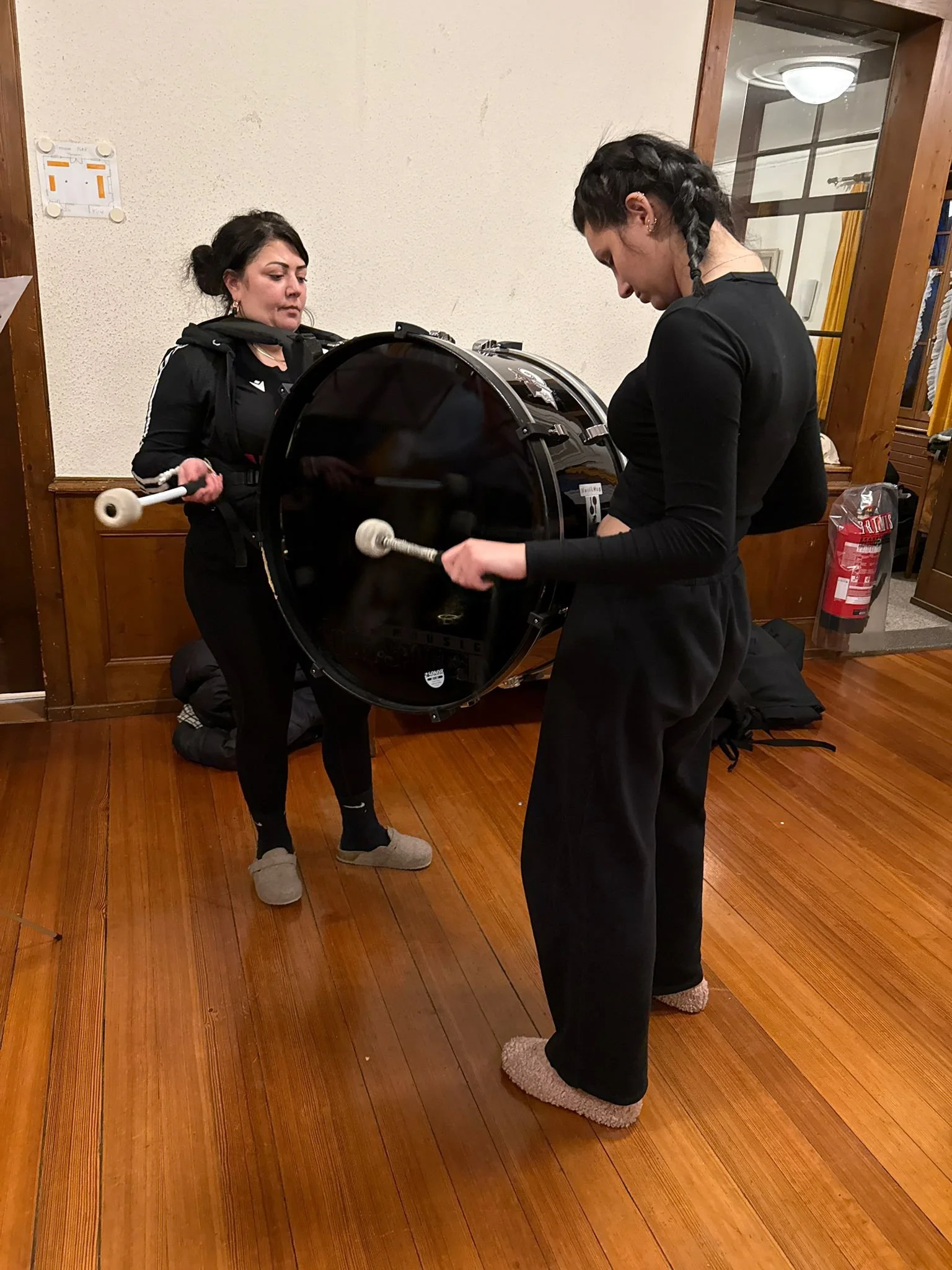 Zwei Frauen spielen auf einer snare, die in der Mitte gehalten wird.