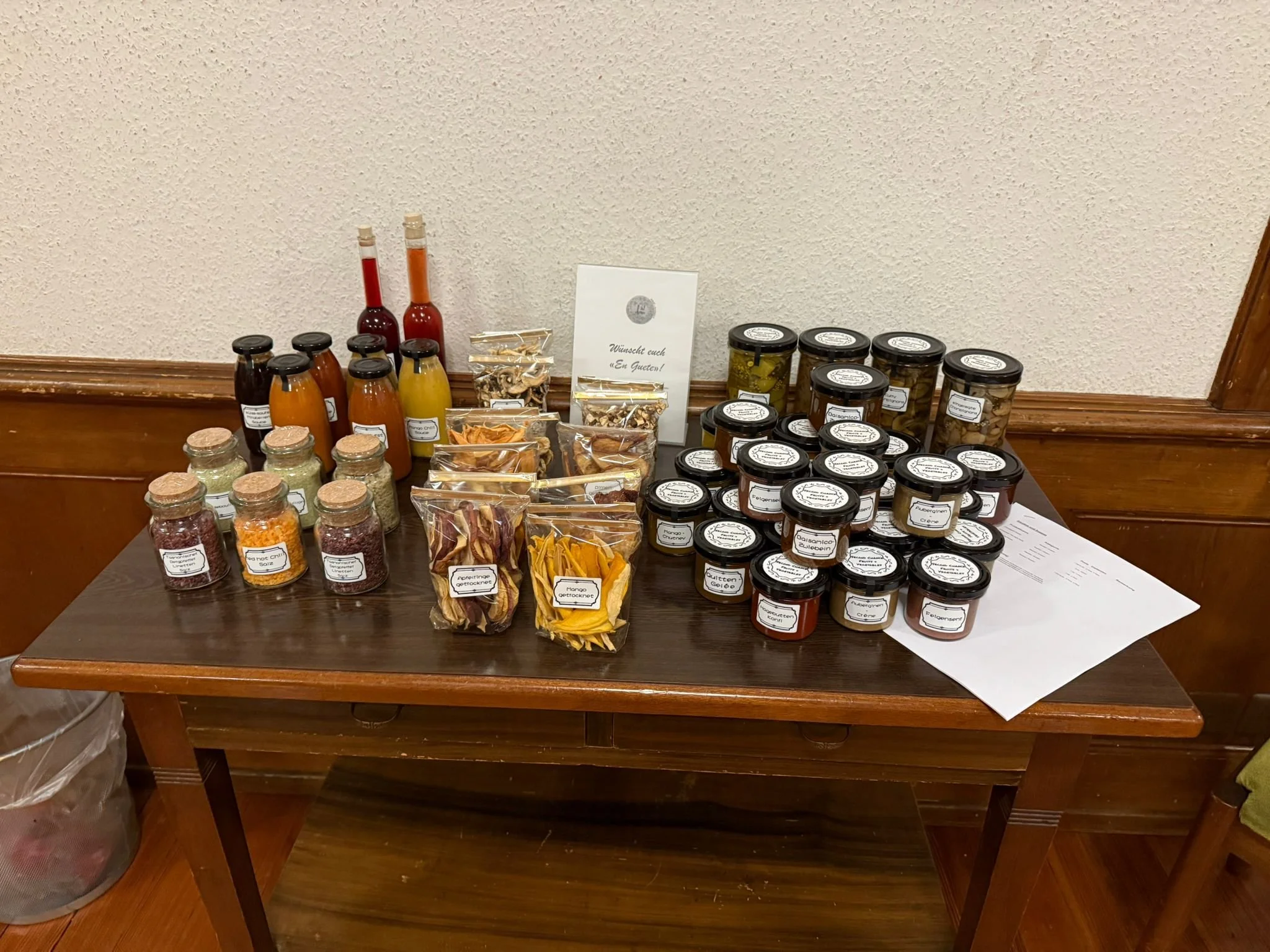 Verschiedene Gläser und Flaschen mit Gewürzen, Saucen und Trockenfrüchten auf einem Holztablett