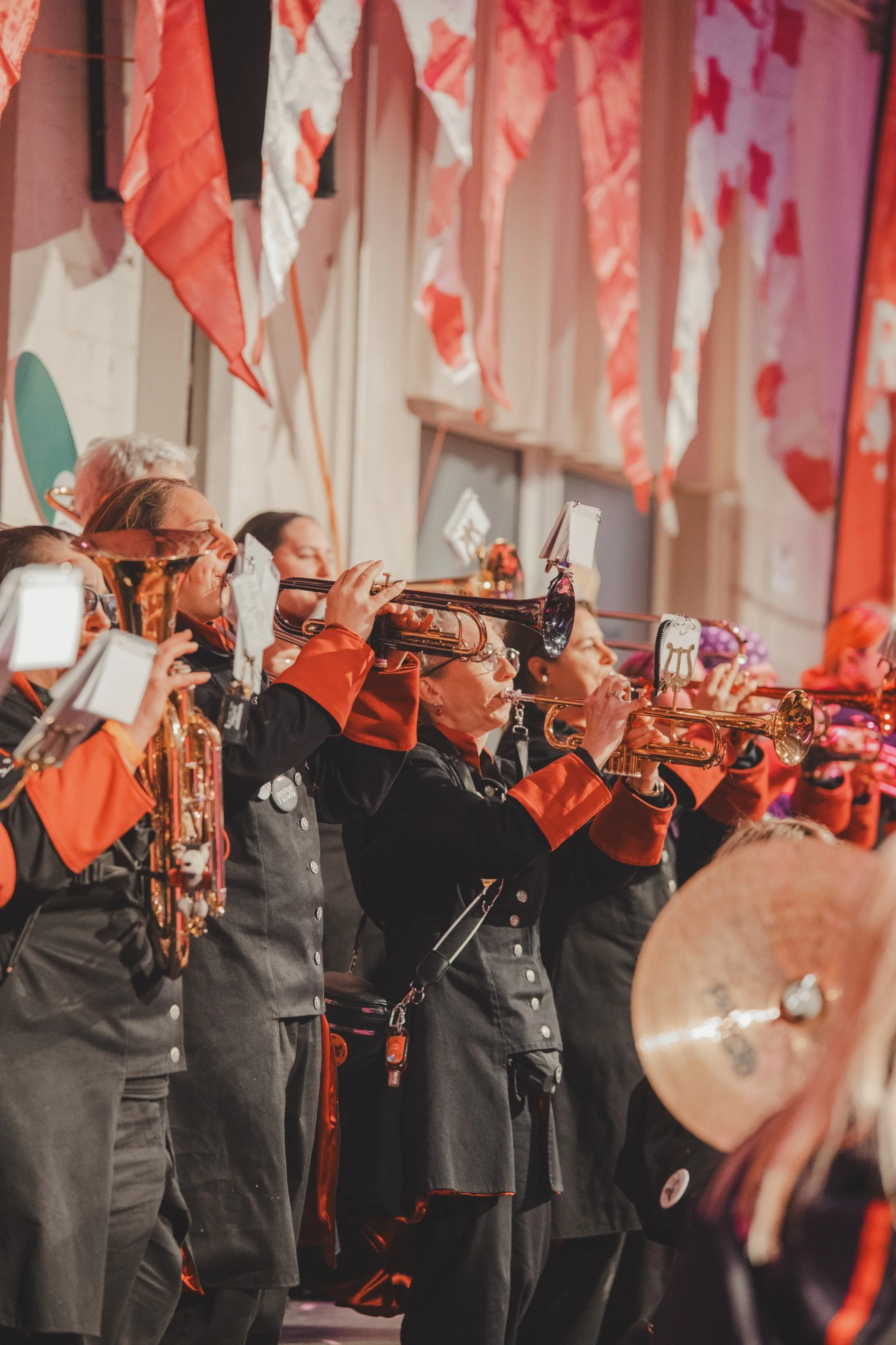Musiker in einer Band, Bariton, spielen Trompeten während eines Auftritts bei einer Veranstaltung, mit roten und schwarzen Kostümen, in einem festlich dekorierten Raum.
