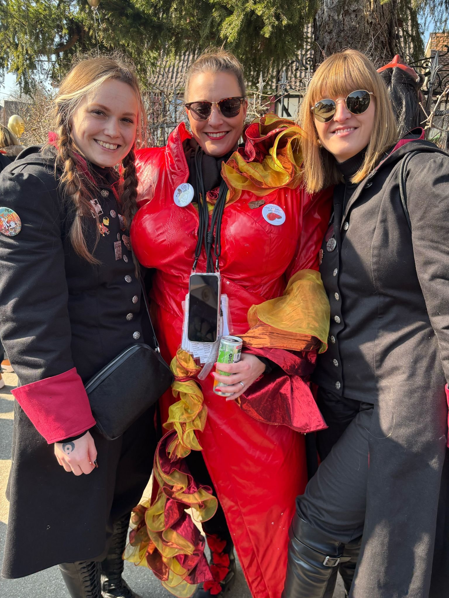 Drei Frauen in bunt gekleideter und fröhlicher Stimmung bei einem Fest oder Karneval.