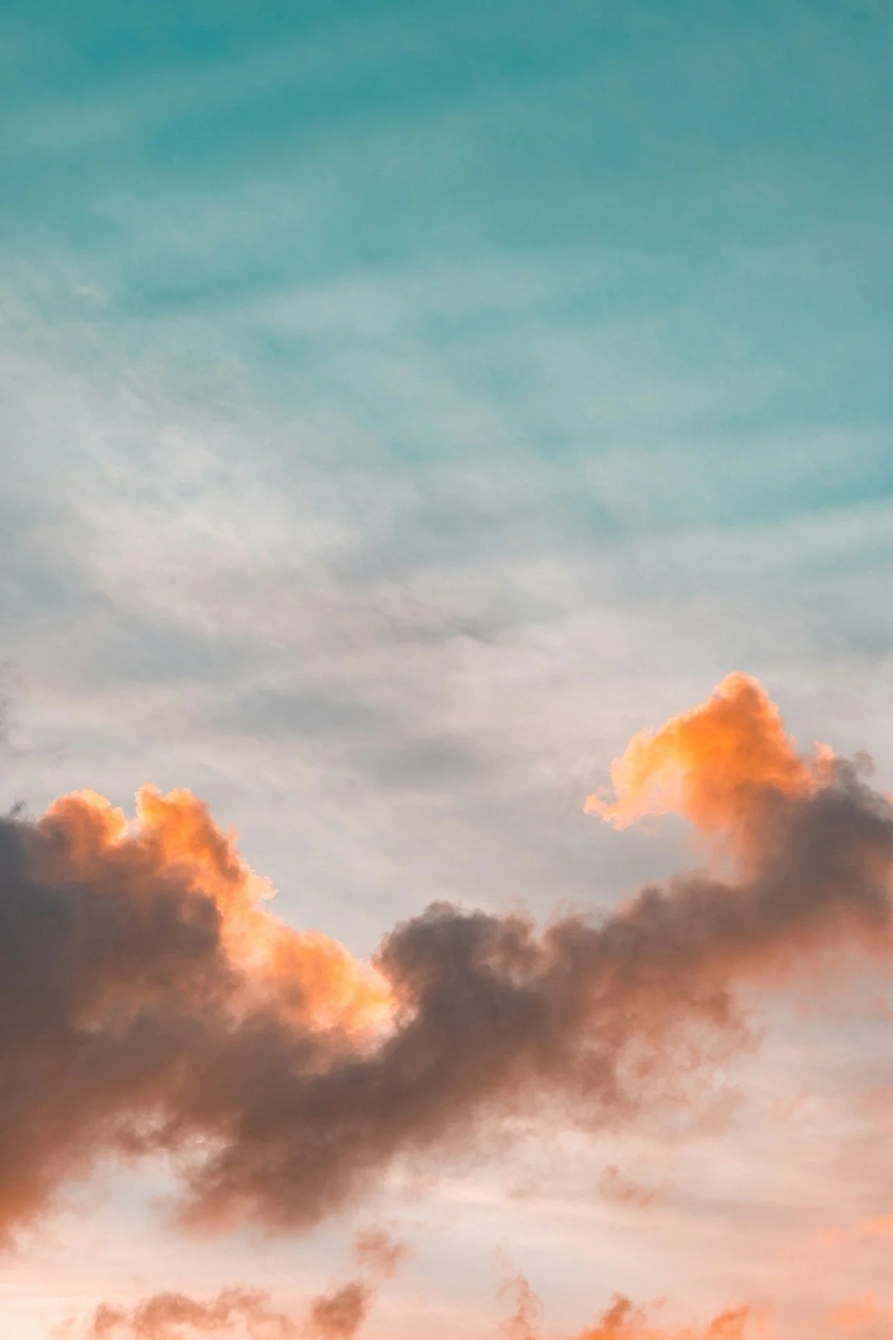 Colorful sunset sky with clouds in shades of orange, pink, and gray against a blue and pastel sky.