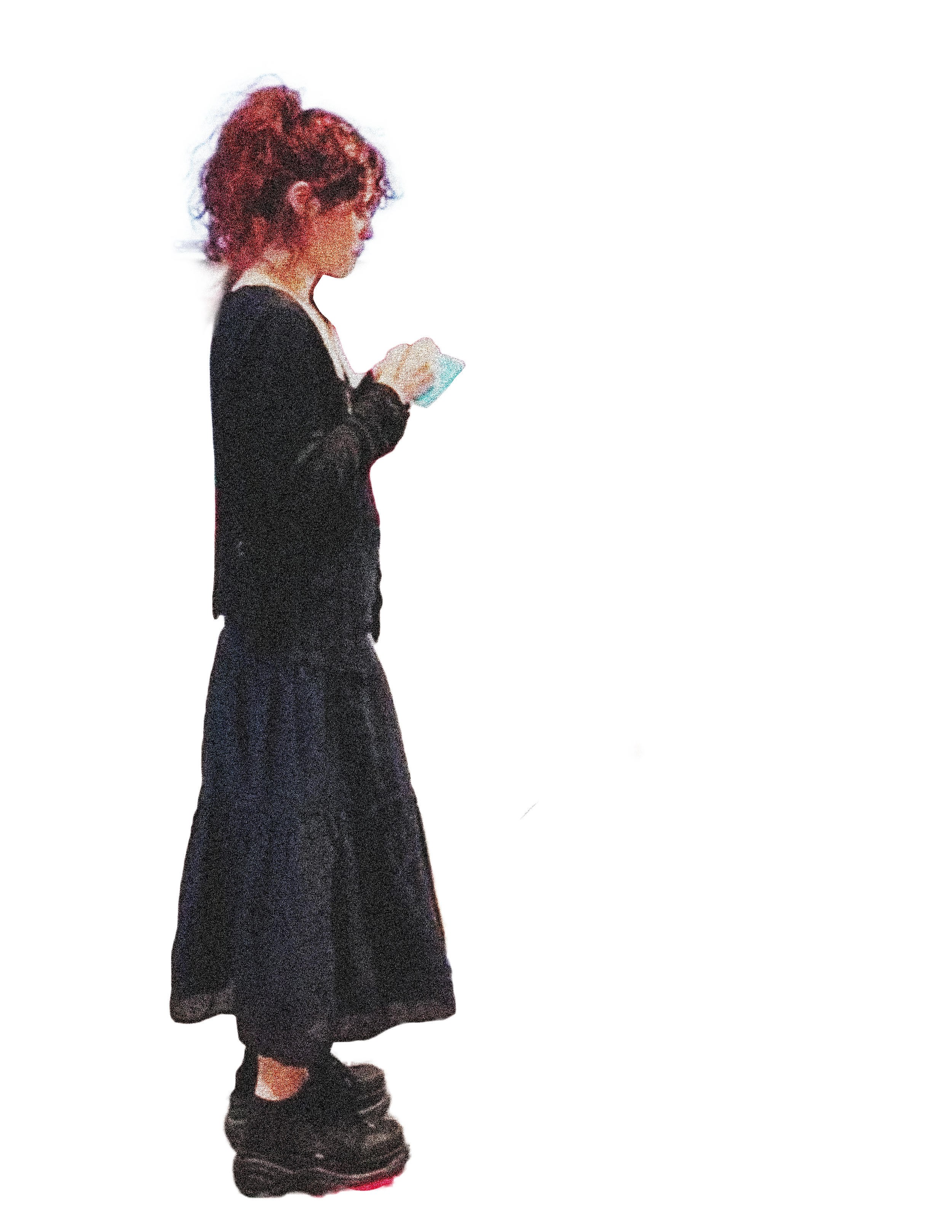 A woman with curly hair wearing glasses, a black dress, and black shoes, walking while looking at her phone.