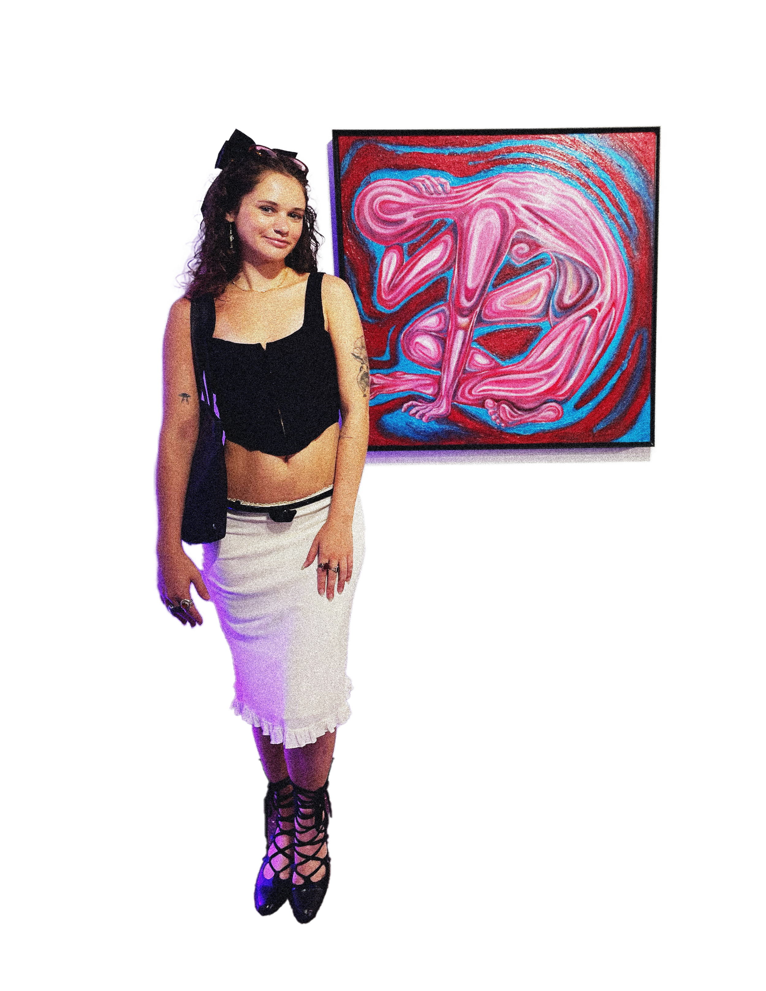 A woman with dark curly hair wearing a black crop top, white skirt, and gladiator style shoes posing next to an abstract pink and red art piece.