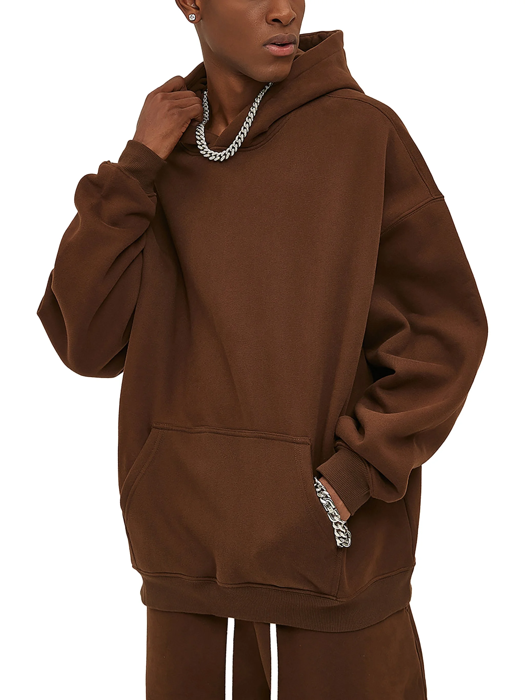 Person wearing a brown hoodie and brown pants, with silver jewelry, against a white background.