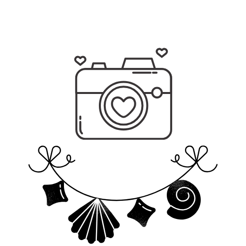 Graphic illustration of a camera with a heart in the center, surrounded by small hearts and decorative hanging charms including a shell, star, and swirl.