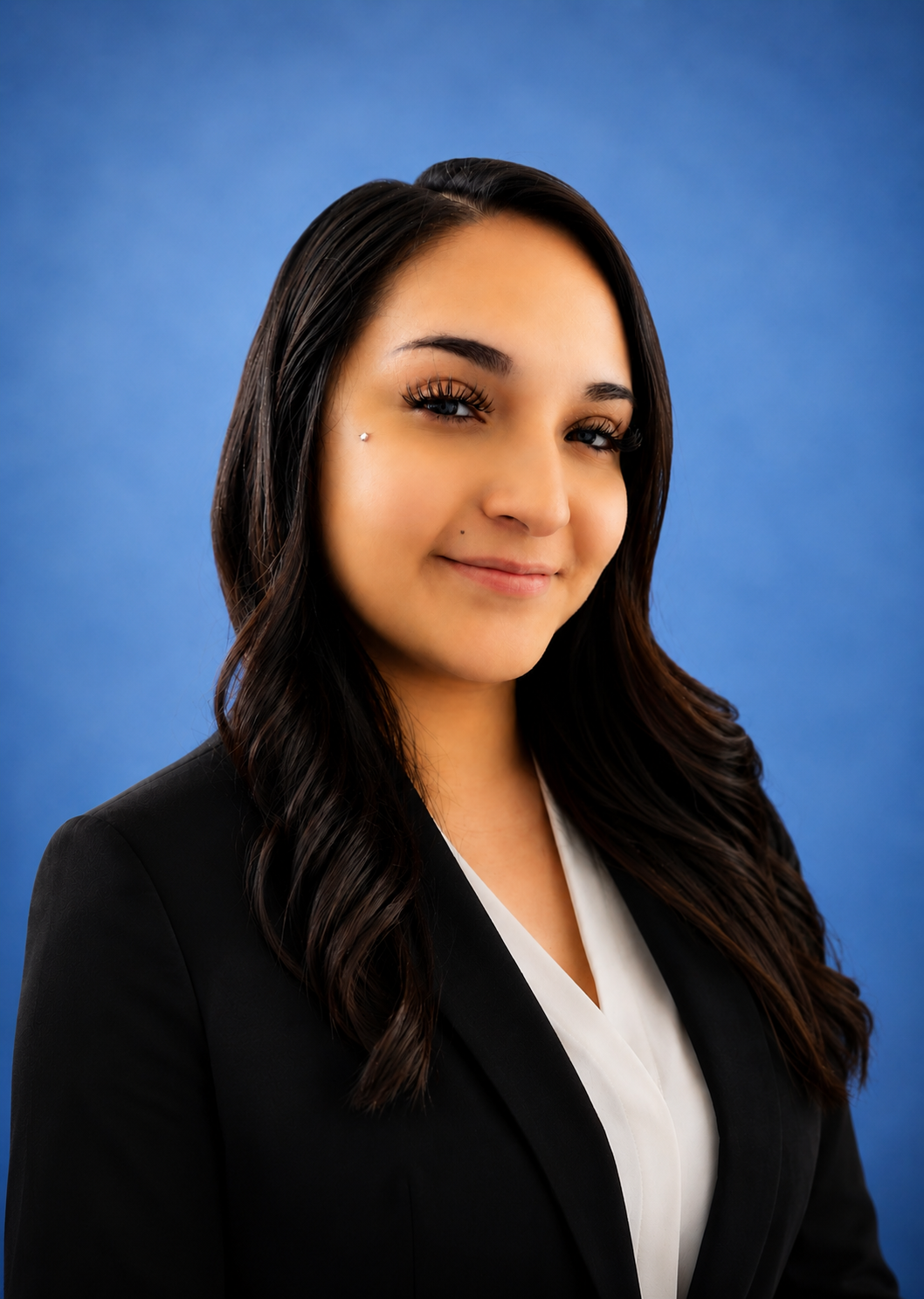 Professional woman with dark hair and makeup, wearing a black blazer over a white blouse, smiling against a blue background.Care Management Green Valley AZ