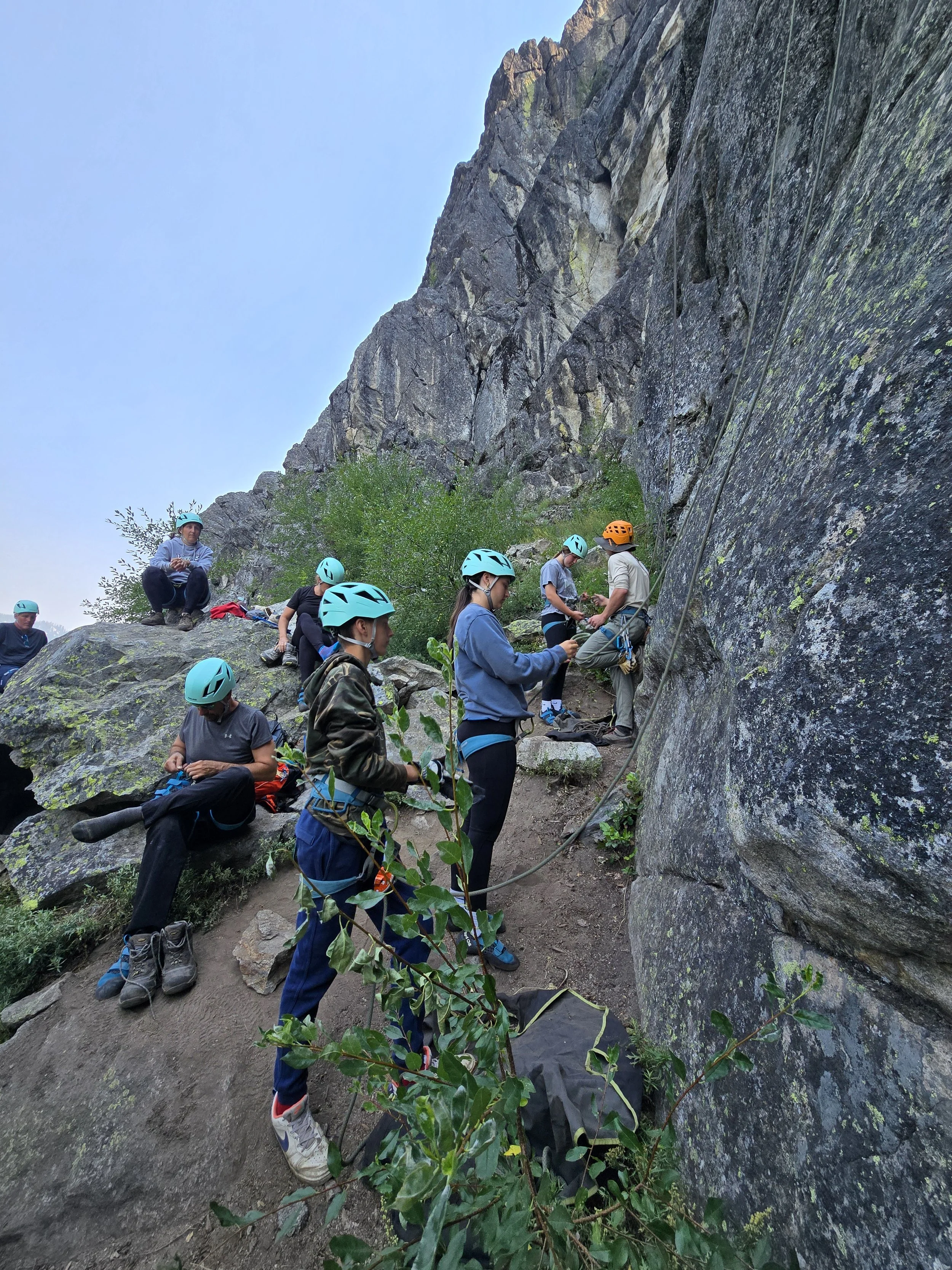 A family gets ready to climb while Co-founder and Lead Guide Collin talks through the belayer-climber safety checks with a climber.