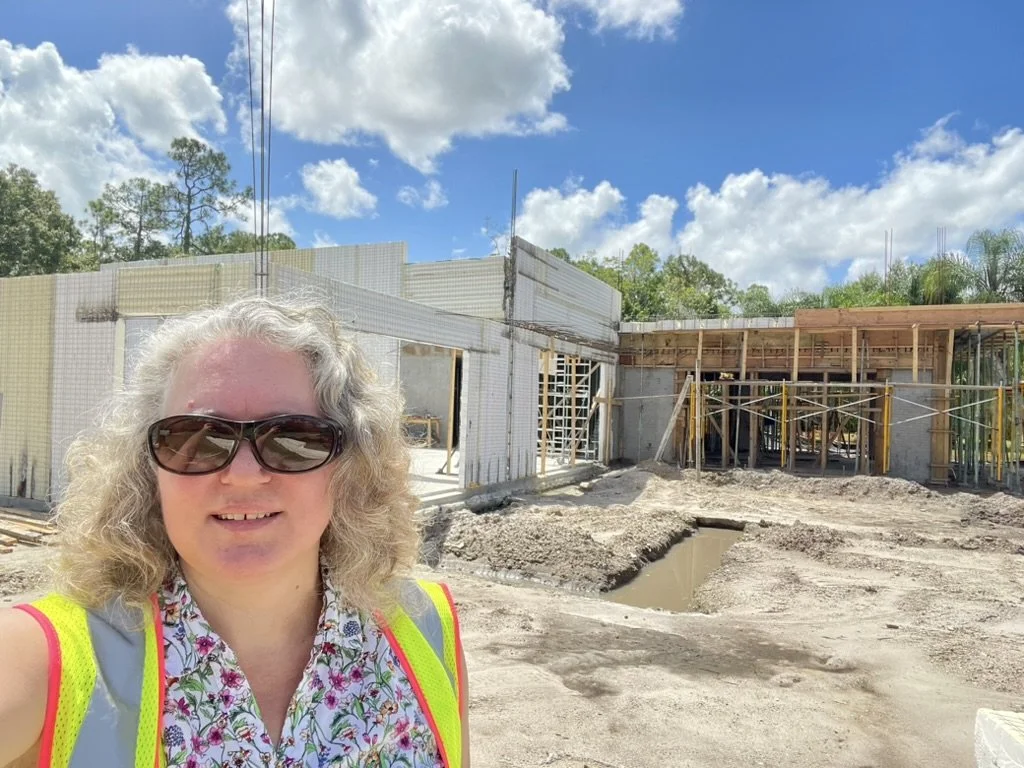 Cathy touring SCIP house under construction showing the wall panels on concrete slab