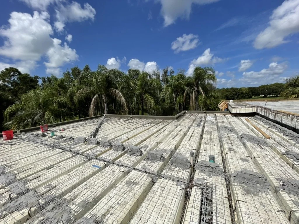 Roof view of horizontal SCIP panels with rebar awaiting concrete, palm trees beyond roof edge