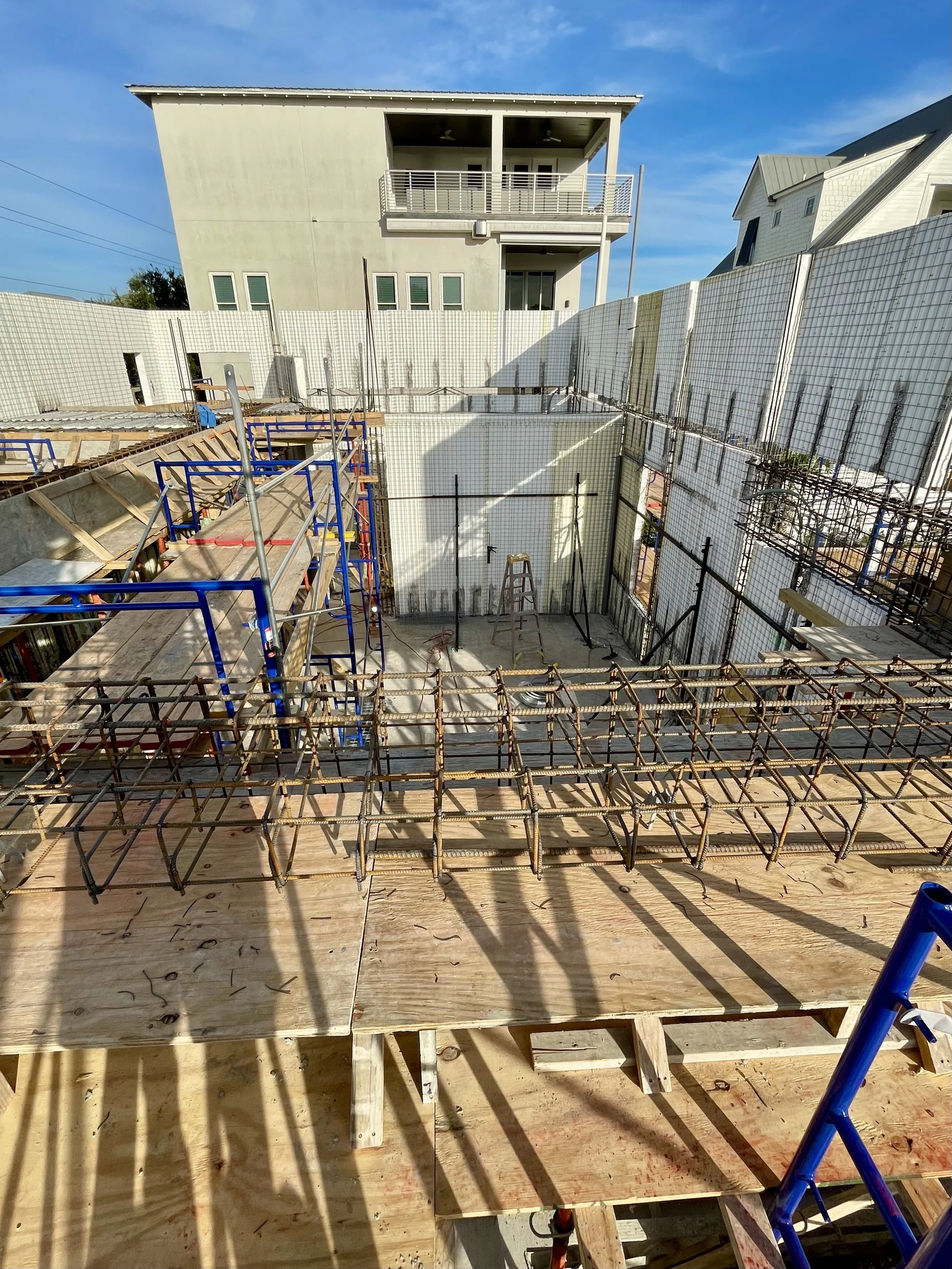 Building under construction with exposed rebar, scaffolding, and SCIP panel walls erected.