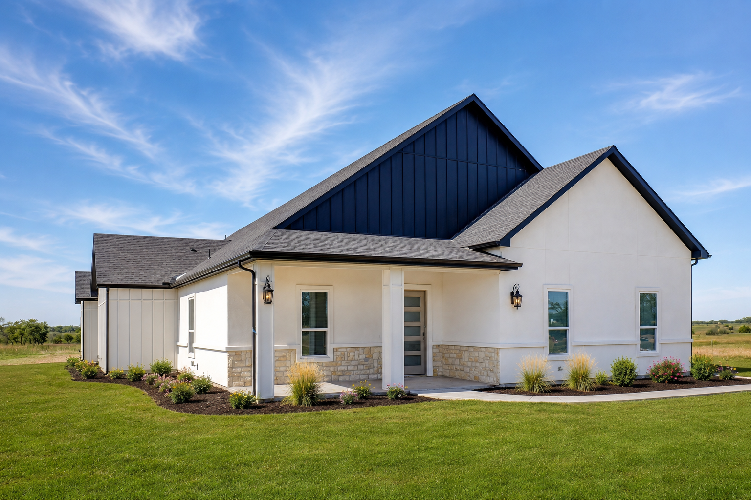 Modern house with white exterior walls, dark blue gabled roof, and stone accents, situated in a rural landscape under clear blue sky.