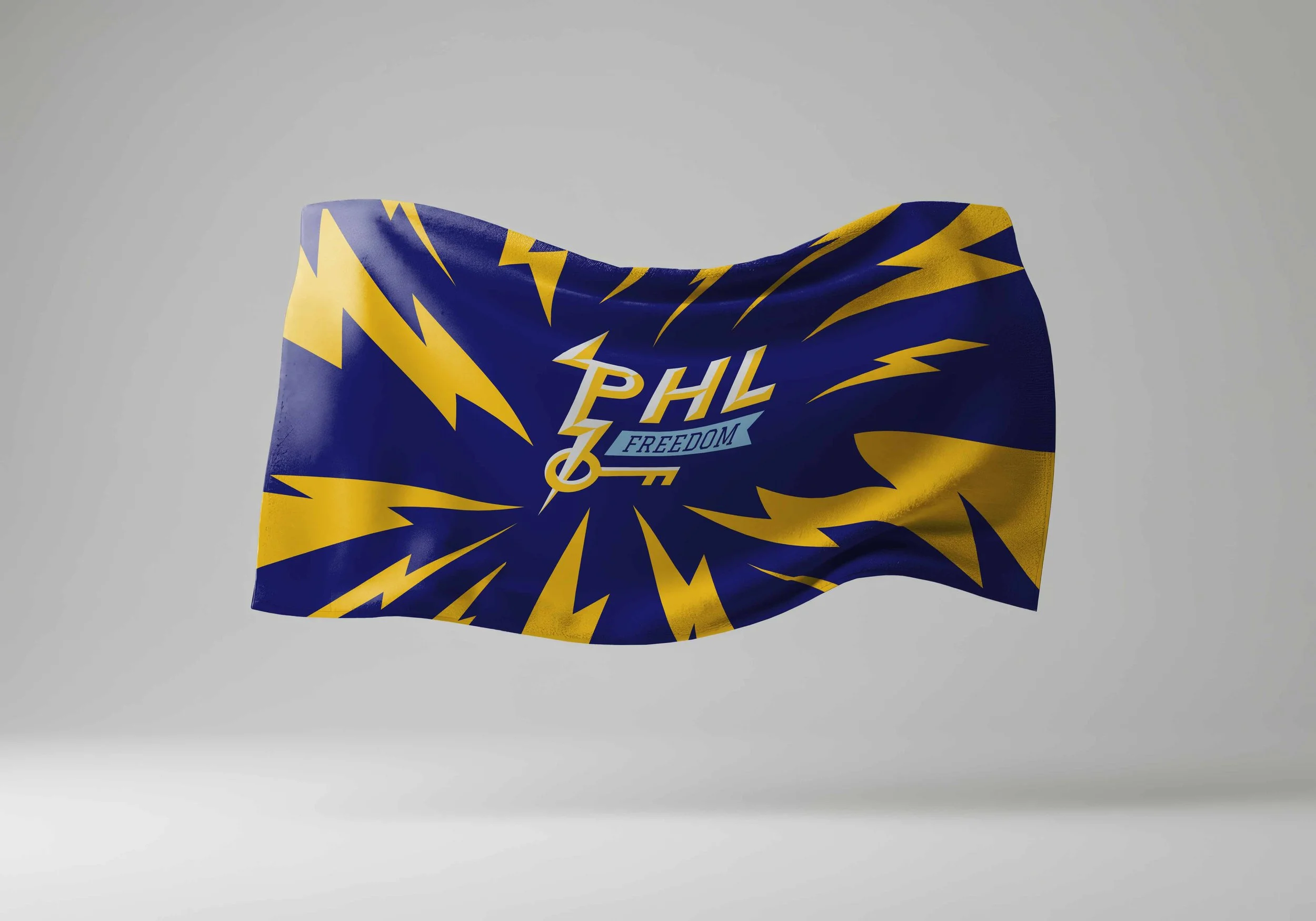 Blue Philadelphia Freedom towel with yellow lightning bolt patterns and the “PHL Freedom” key logo in the center, shown waving against a neutral background.