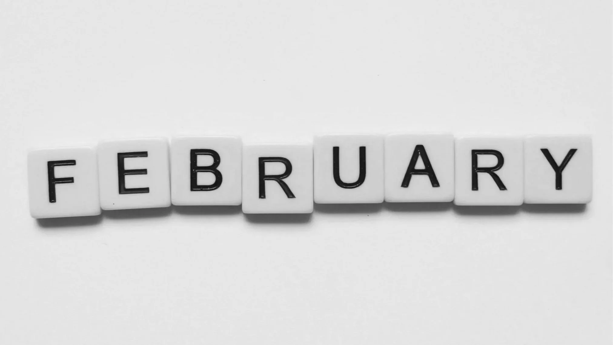 Black and white photo of letter tiles spelling out February.
