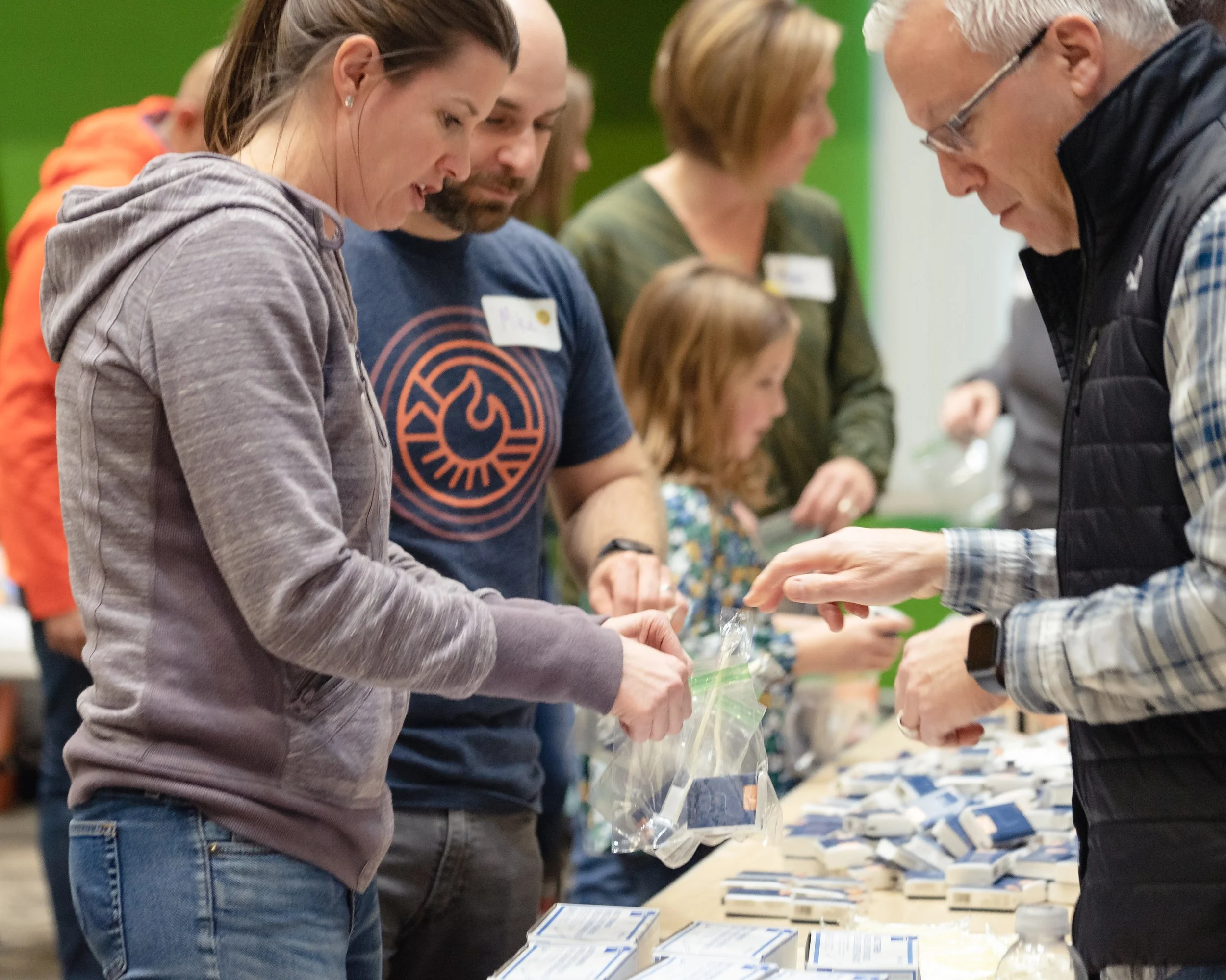 People participating in an event, with a woman and man engaging at a table with various items.