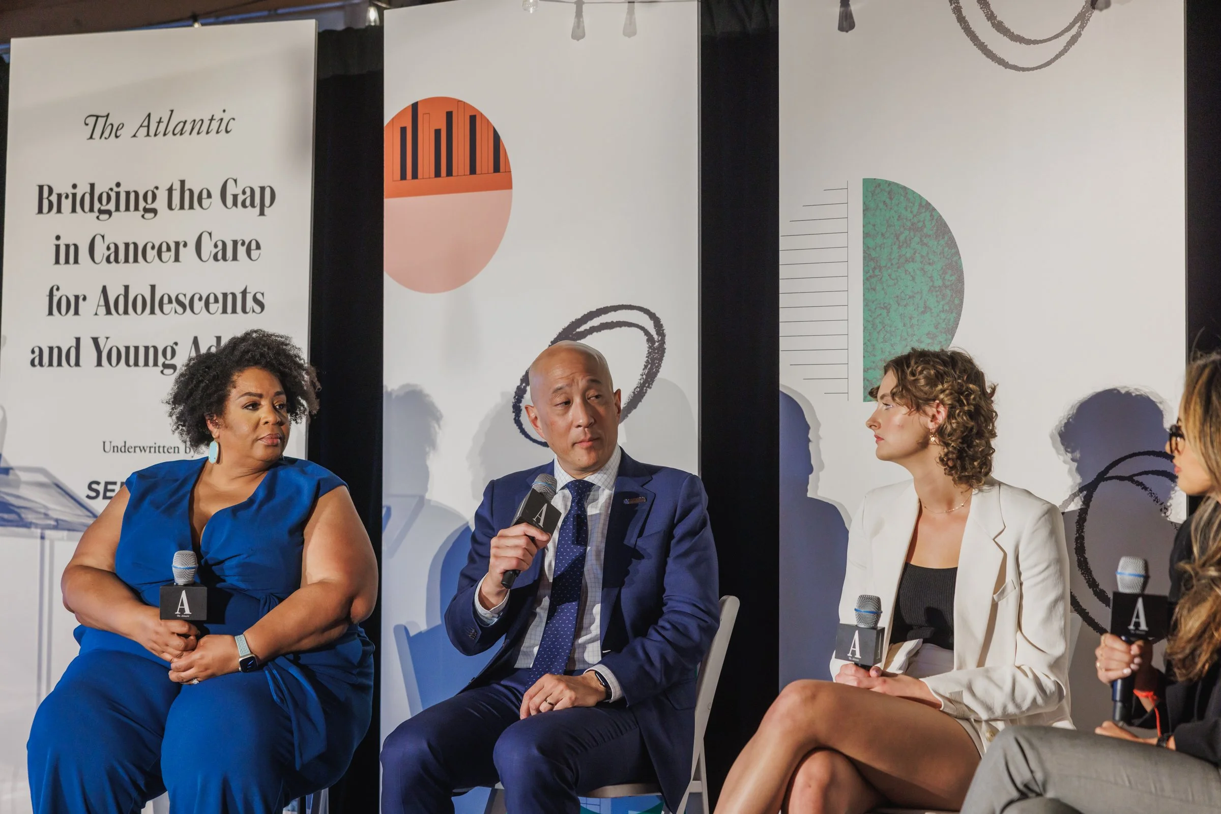 Four people seated on a stage participating in a panel discussion, holding microphones. A banner behind them reads 'Bridging the Gap in Cancer Care for Adolescents and Young Adults'.