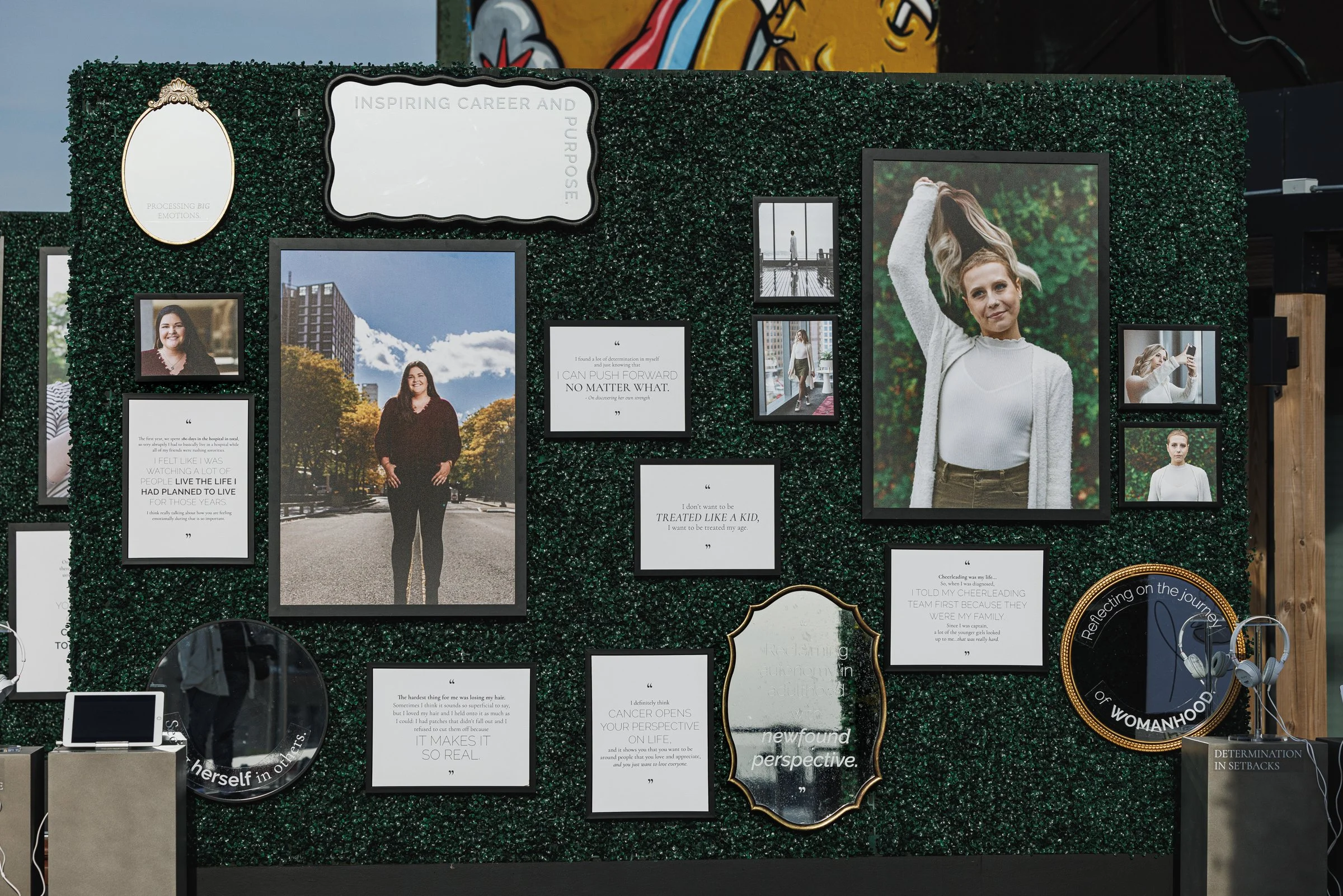 Decorative wall with framed photos, quotes, and mirrors. Large portrait of a woman with blonde hair holding her hair up, surrounded by other smaller images and inspirational quotes. Earphones hanging from a stand to the bottom right.