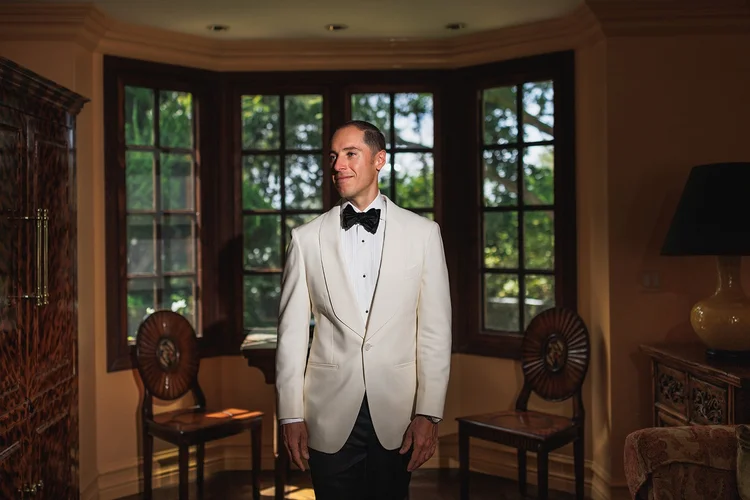Groom in a white dinner jacket in a wood-panelled room