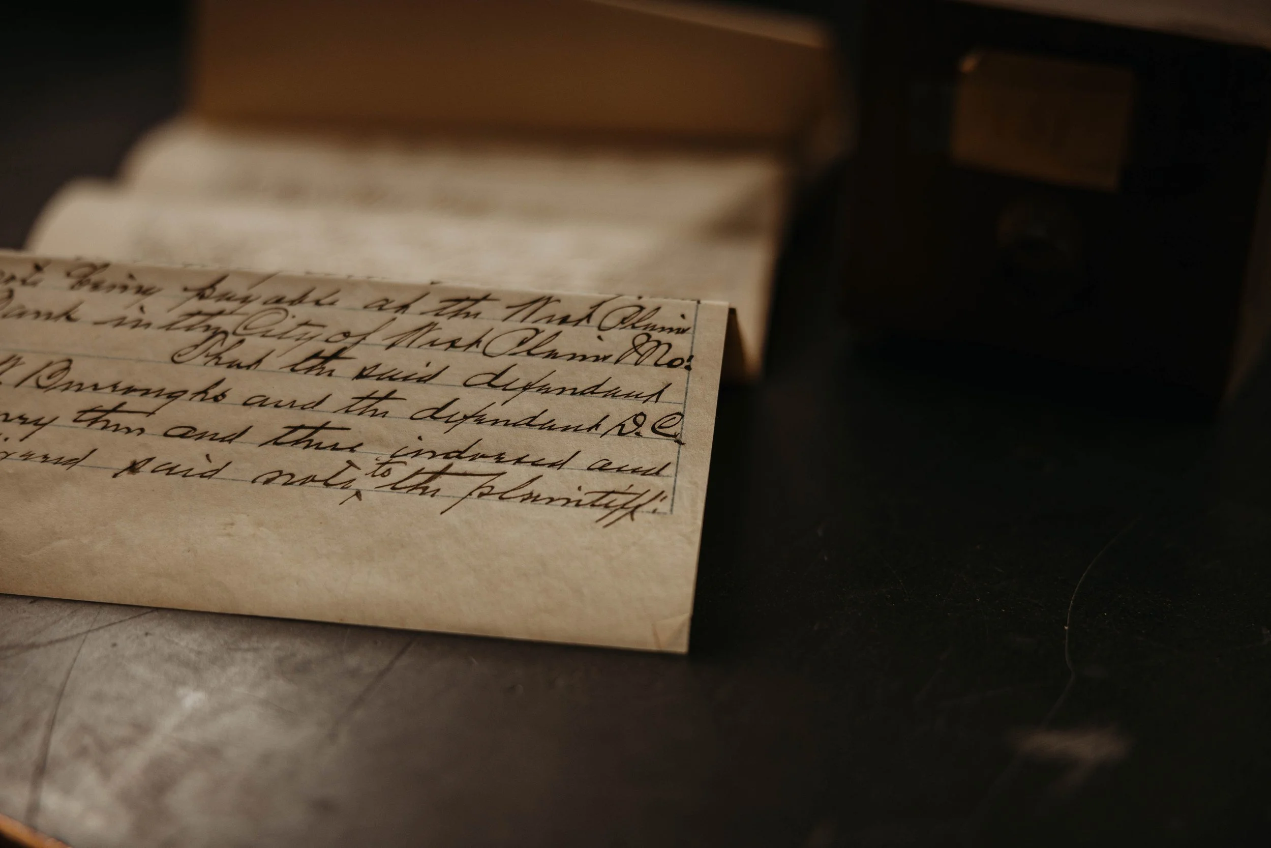Close-up of an aged handwritten letter or document with cursive writing on slightly yellowed paper, partially visible in the foreground.