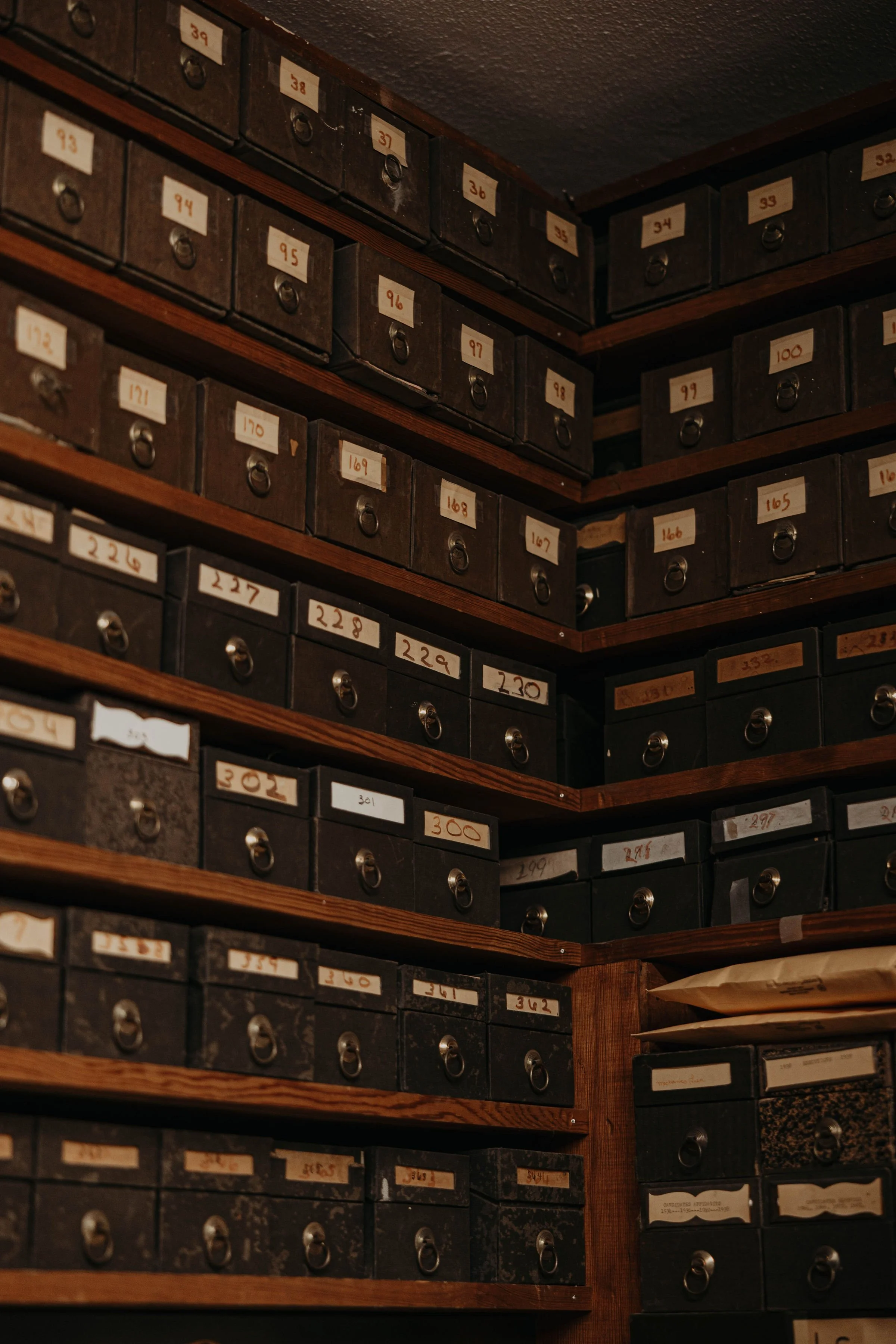 A wooden shelving unit filled with small dark drawers, each labeled with handwritten numbers.