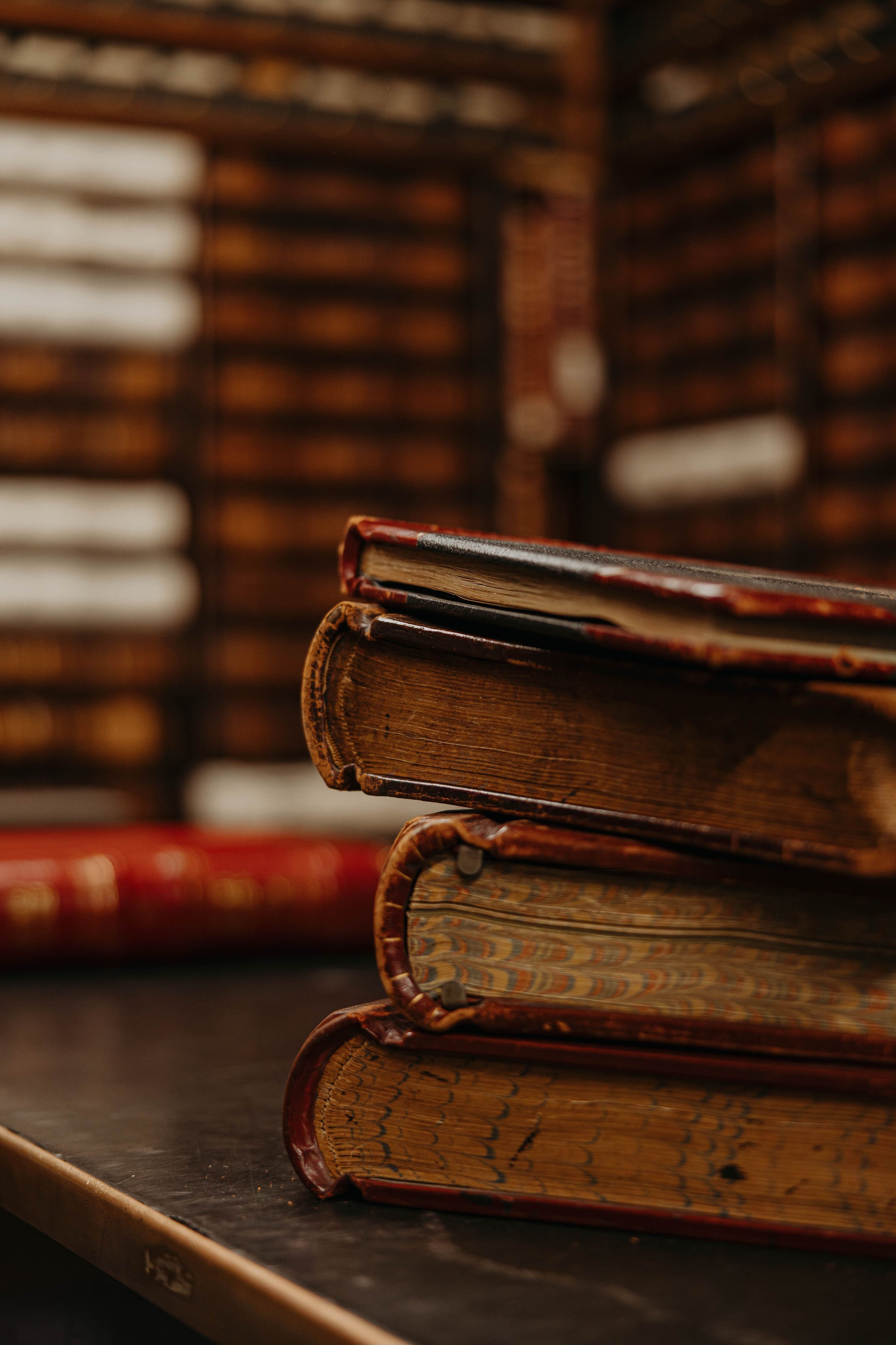 Close-up of vintage books stacked on a dark surface with a wooden background.
