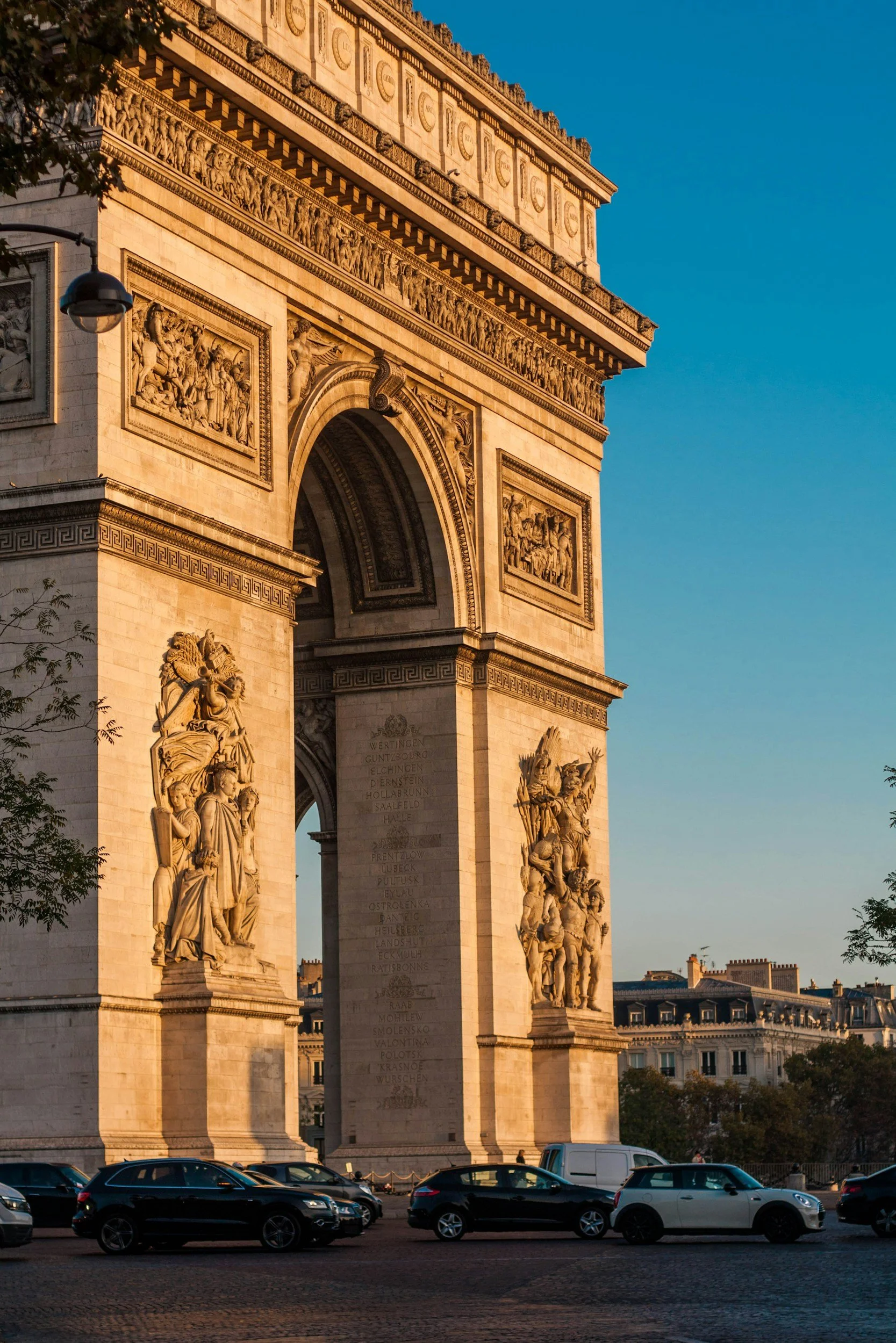 The Arc de Triomphe, a large Parisian monument, is shown in this photo during the day with clear blue sky overhead.