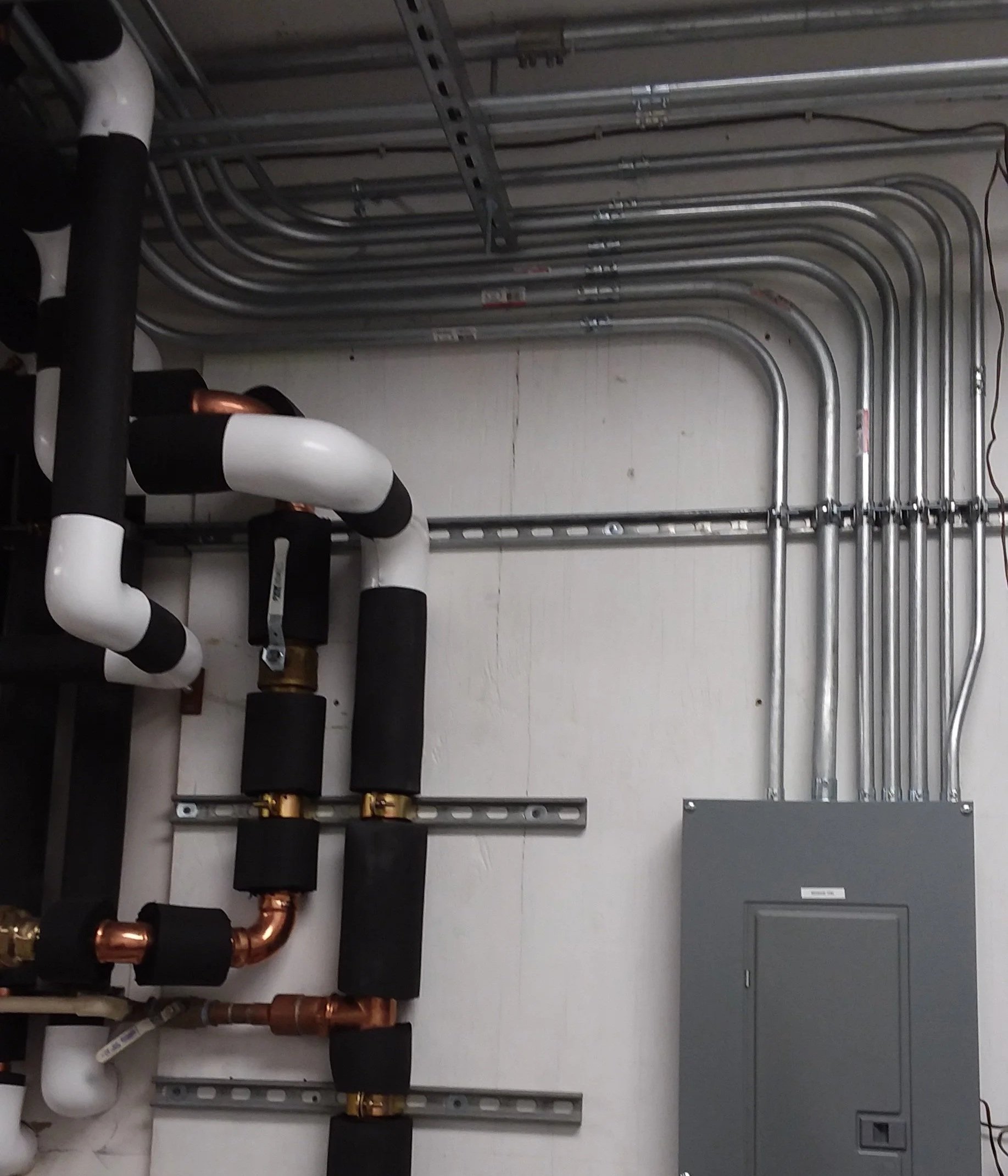 Wall showing multiple EMT conduit bent in neat pattern exiting a service panel.