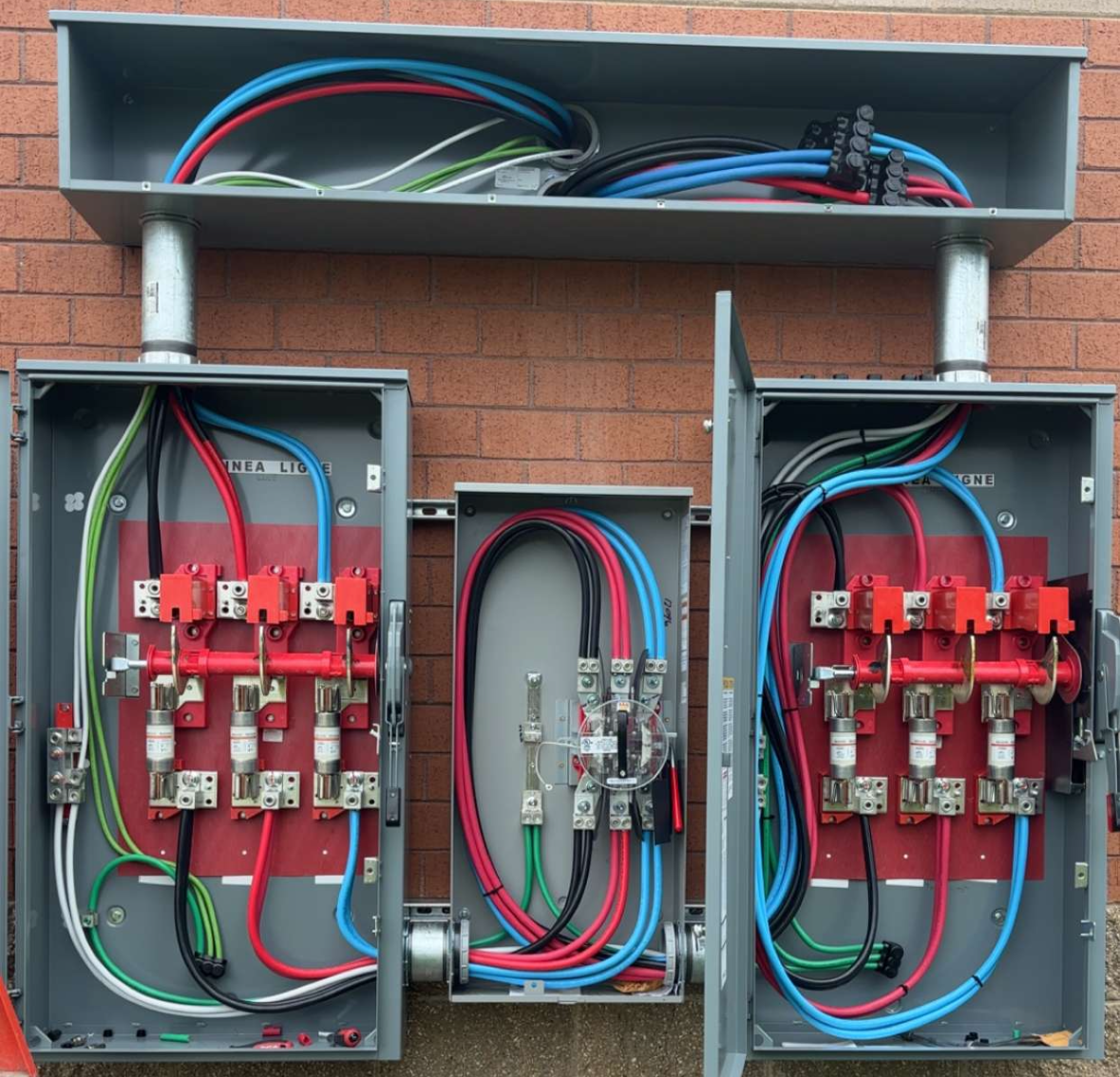 Three large grey cabinets with multi-colored large wires running between them.