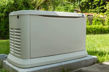 A white colored back-up generator on a concrete pad sitting in a yard.