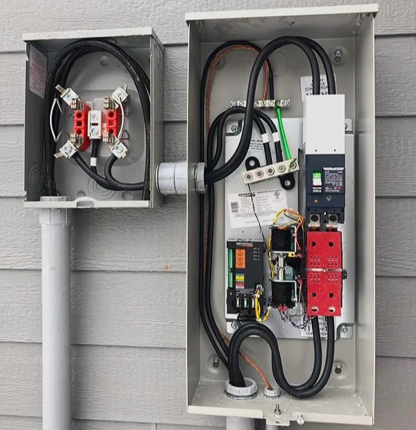 Two grey metal electrical cabinets showing wiring between a meter socket and a generator transfer switch.