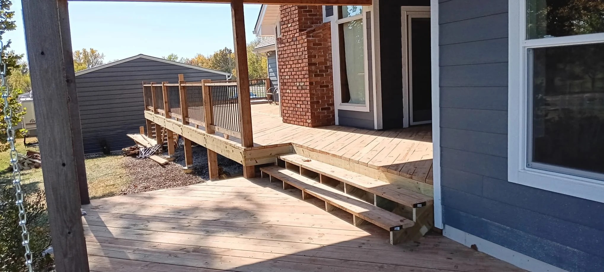 A newly built wooden deck with black metal spindles, stairs down to a secondary deck.