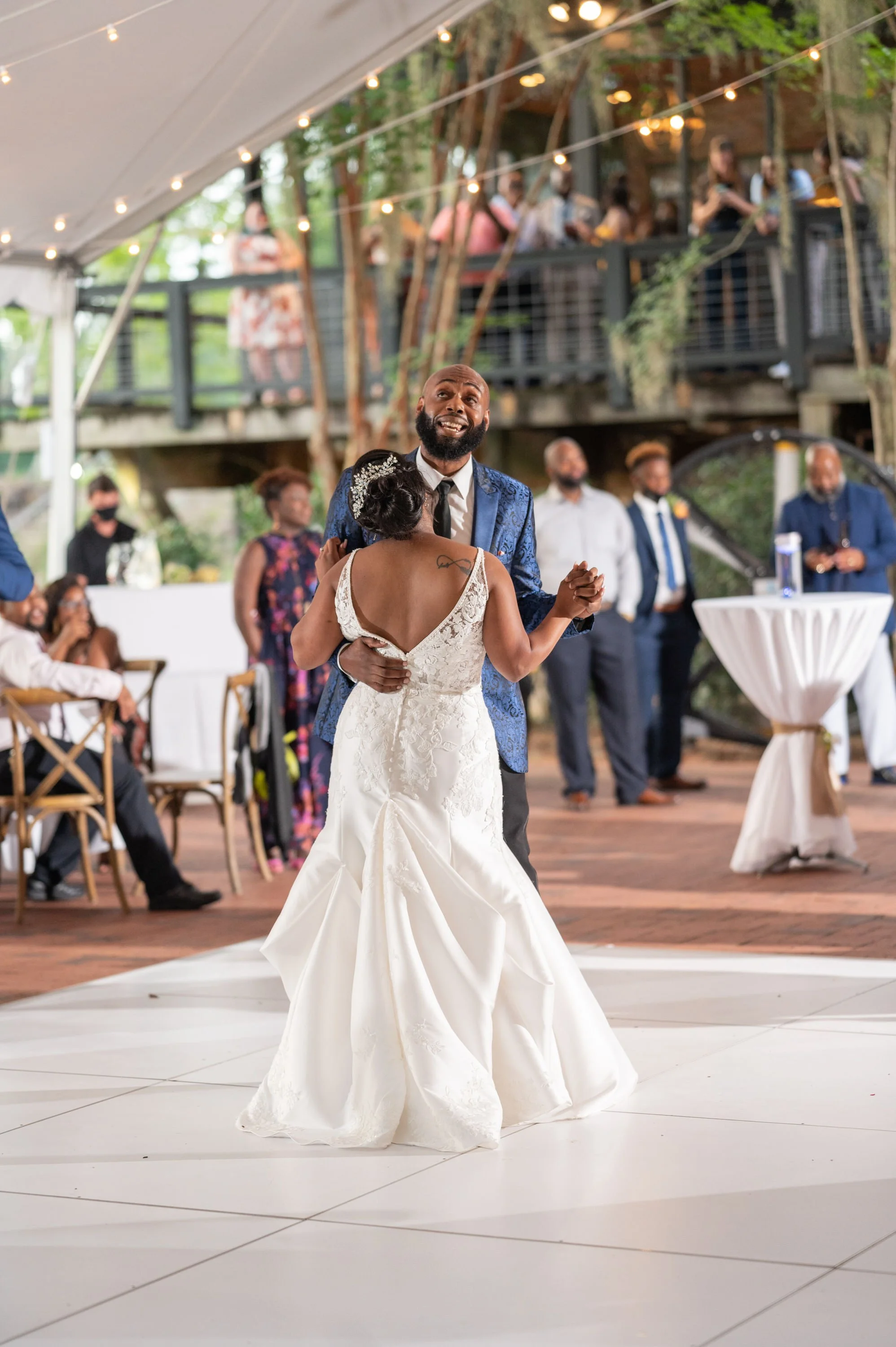 A bride and groom dancing at their wedding reception with guests watching in the background.