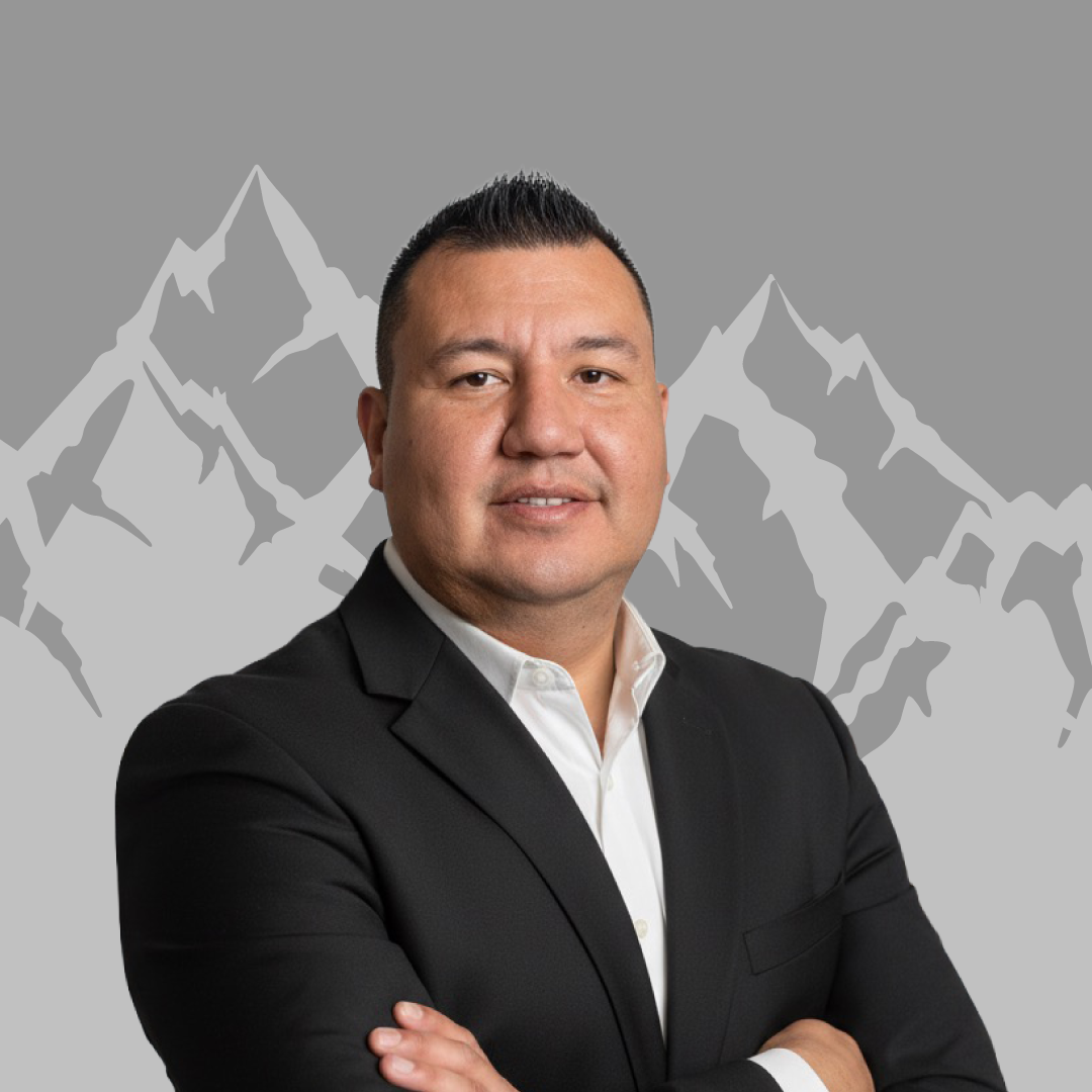 A man in a black suit crossed arms, standing in front of a stylized mountainous background.