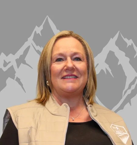 woman smiling in front of a mountain background