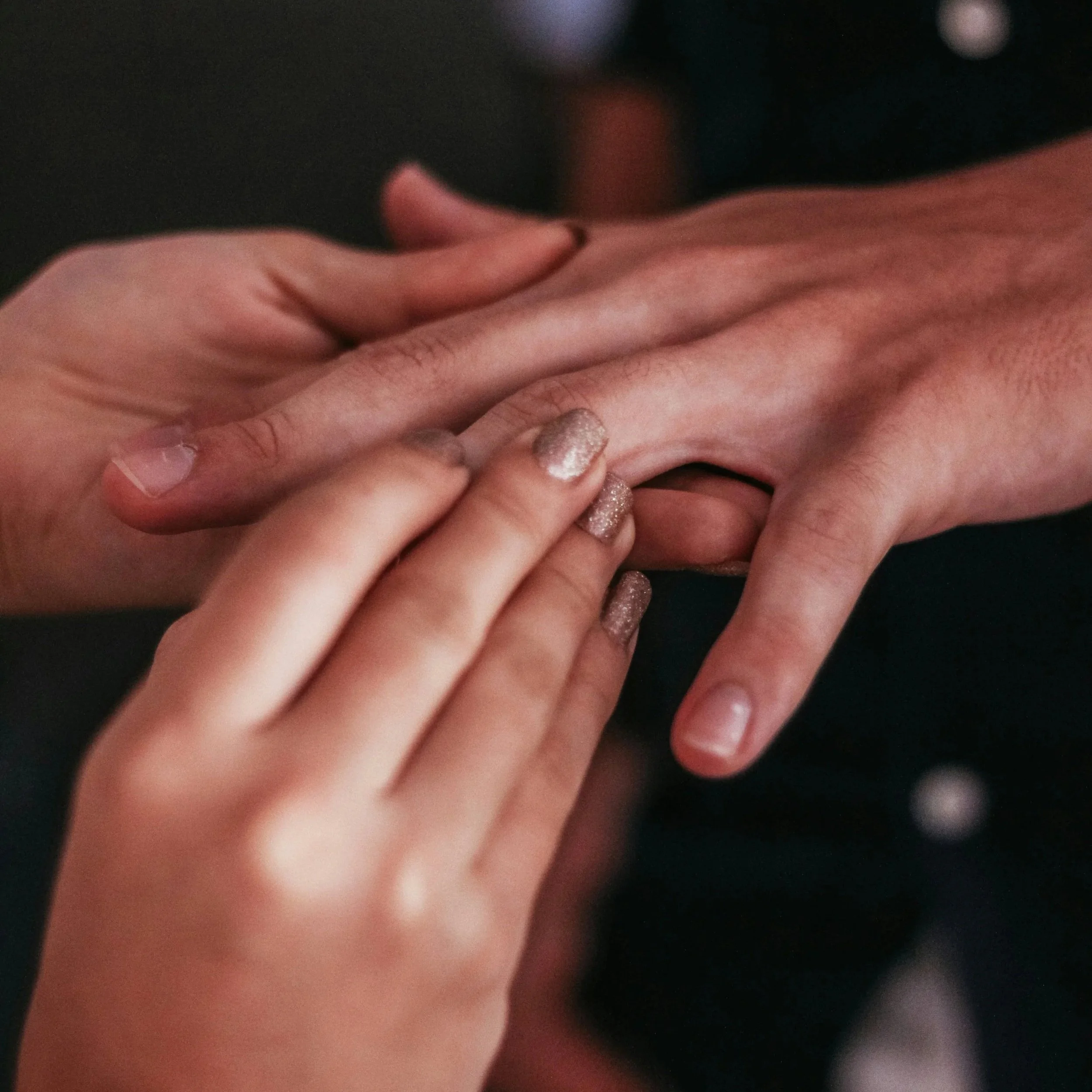 Close-up of a person's hand being gently held by a therapists fingers intertwined, while the acupressure therapist in Easton, MD brings awareness and energy through the hand and fingertips
