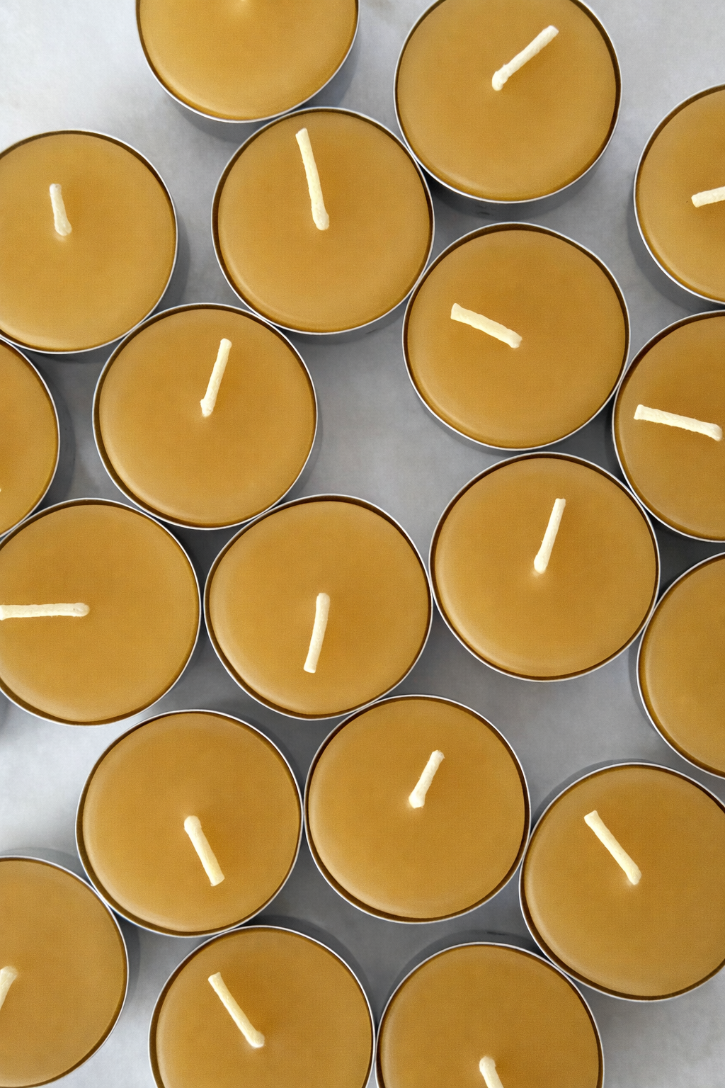 Several brown candles with white wicks arranged on a gray surface.