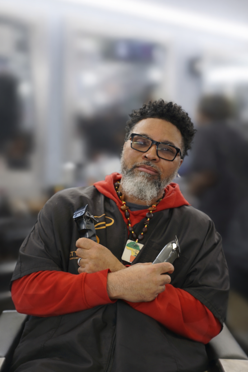 Logo for Stylz & Trendz, a professional barbering business established in 2005, featuring a red barber's cape and scissors with a red and blue circular border.