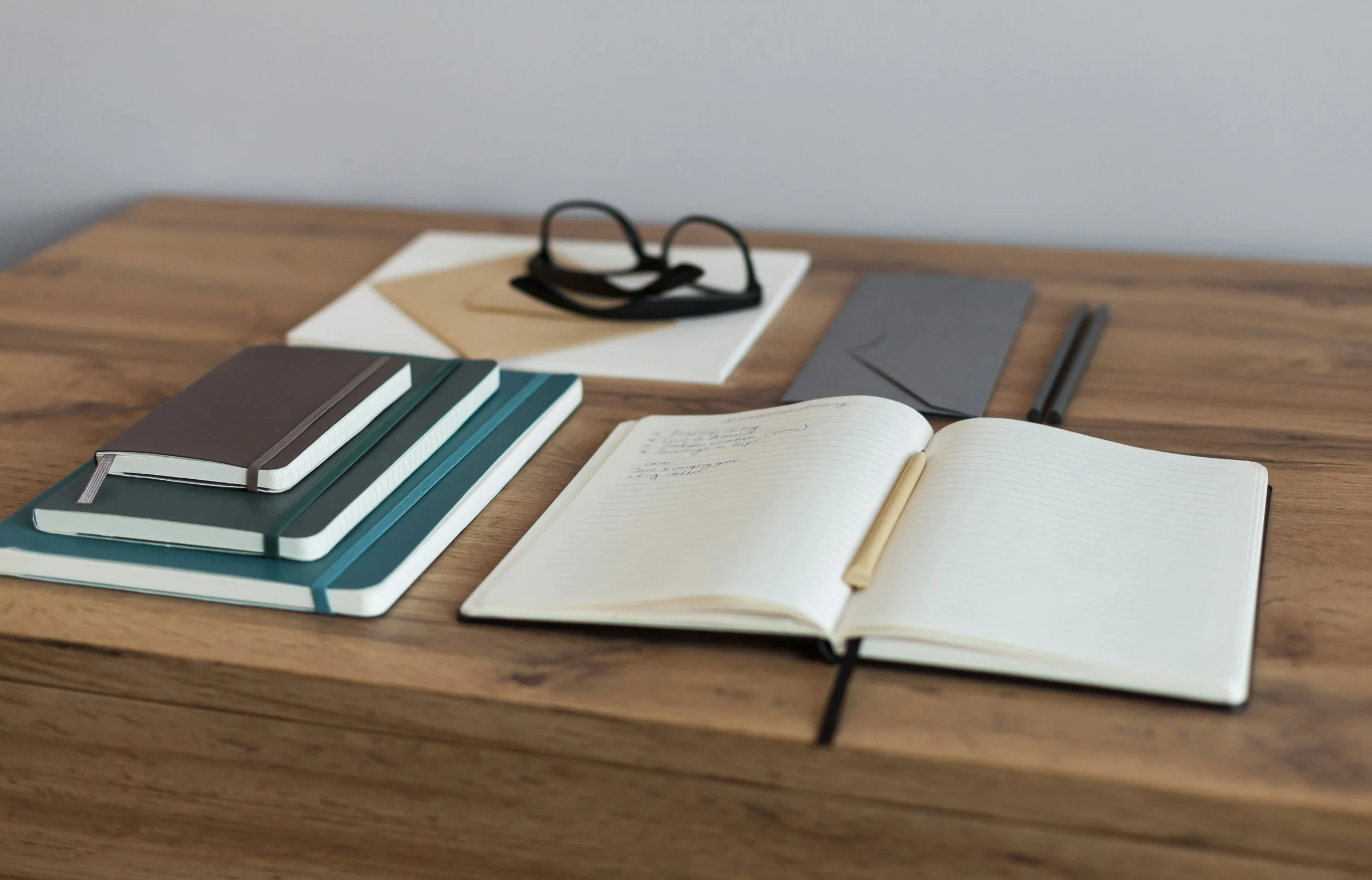 Notebook, books, and reading glasses on a desk representing reflective leadership and writing